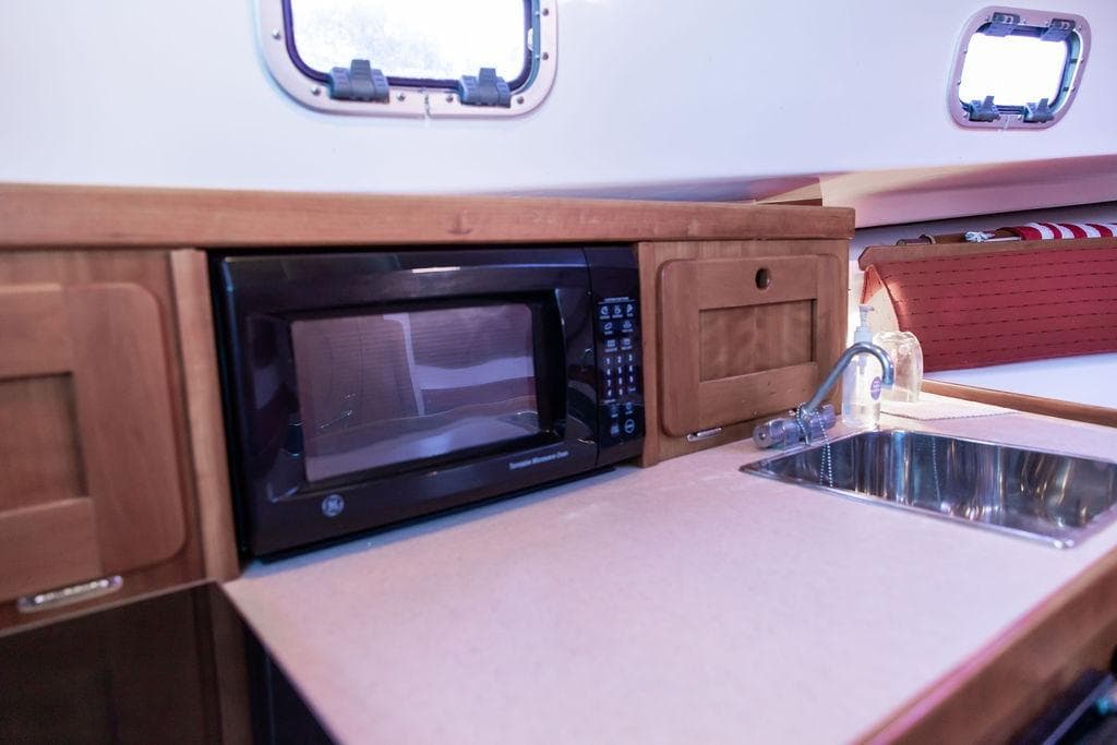 2008 Hunt Yachts Surfhunter 29 interior with microwave and sink in wooden cabinetry.