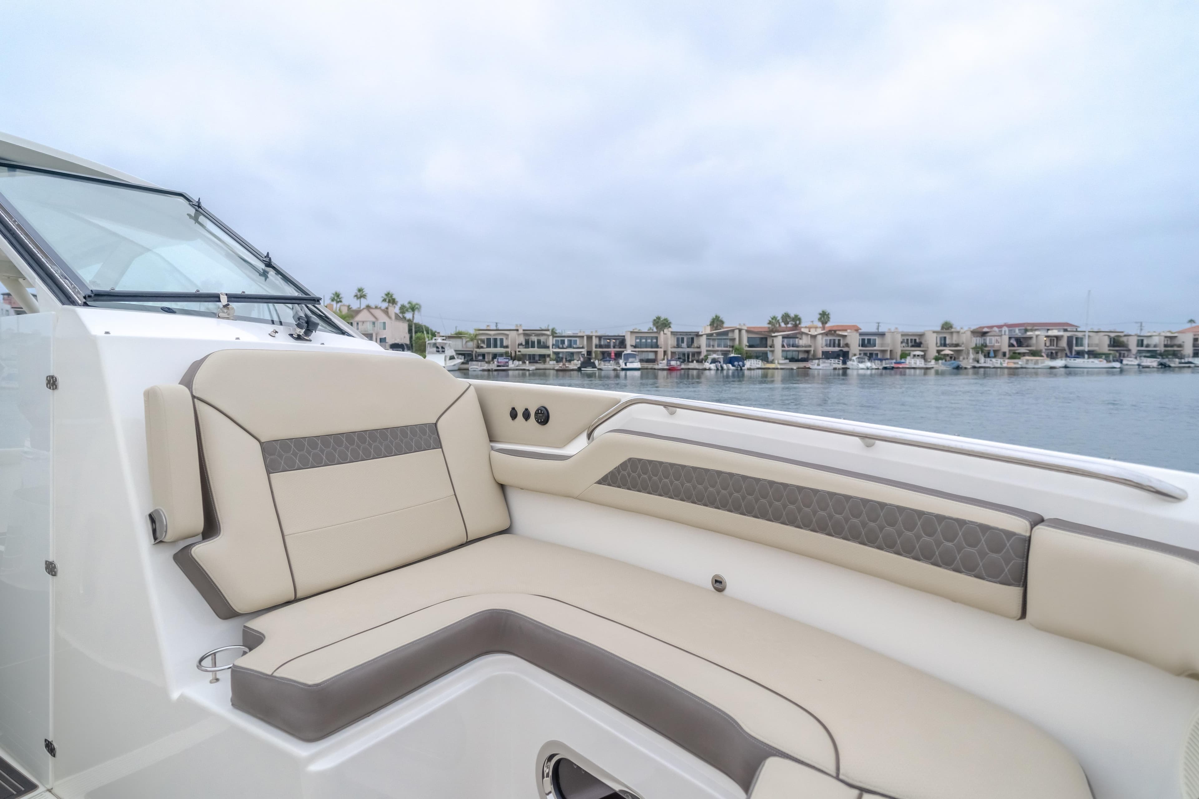 Luxurious 2018 Pursuit boat interior with beige seating, overlooking waterfront homes.