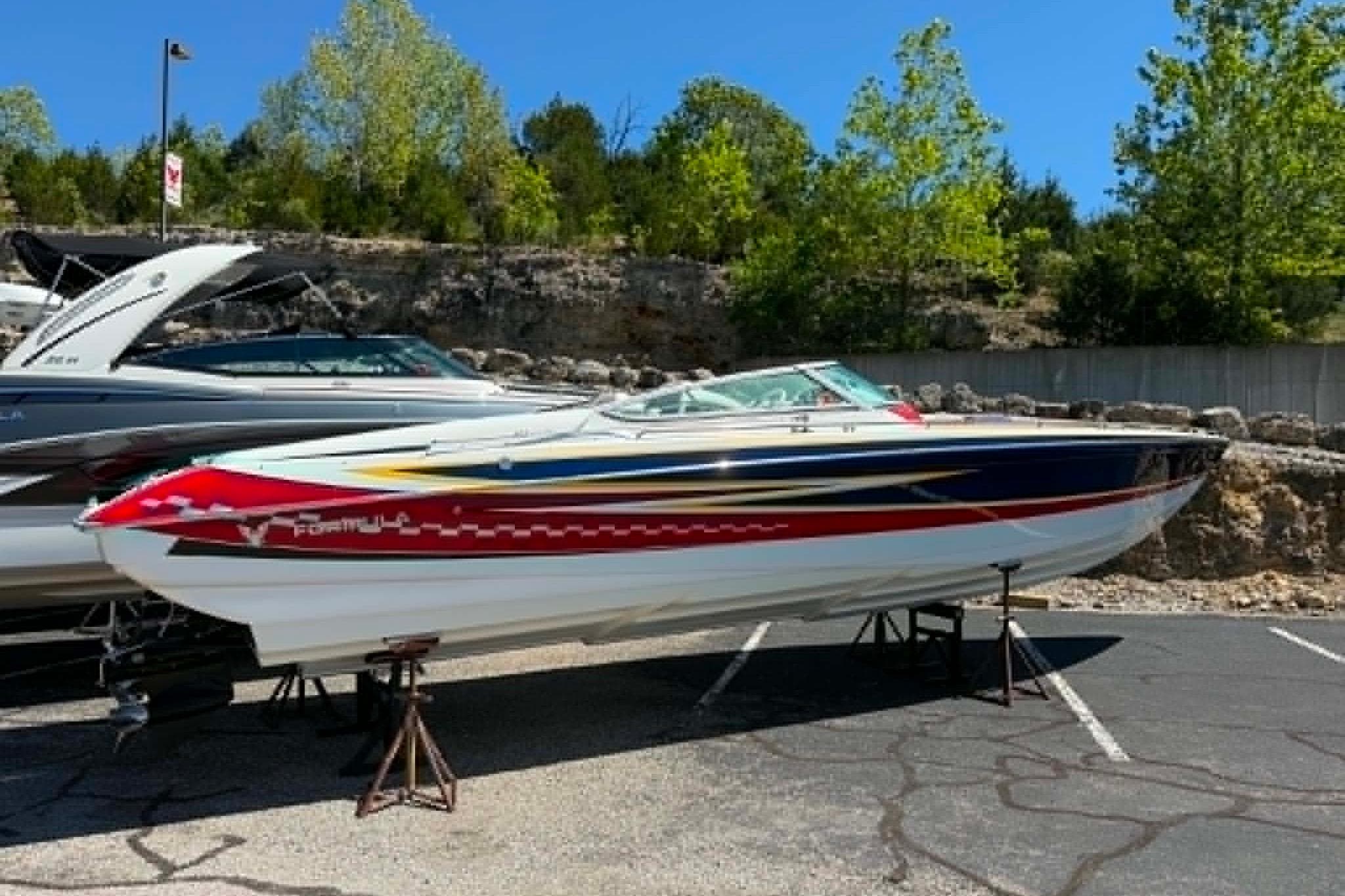 2007 Formula 353 FASTech boat displayed outdoors on stands, vibrant design, sunny day.
