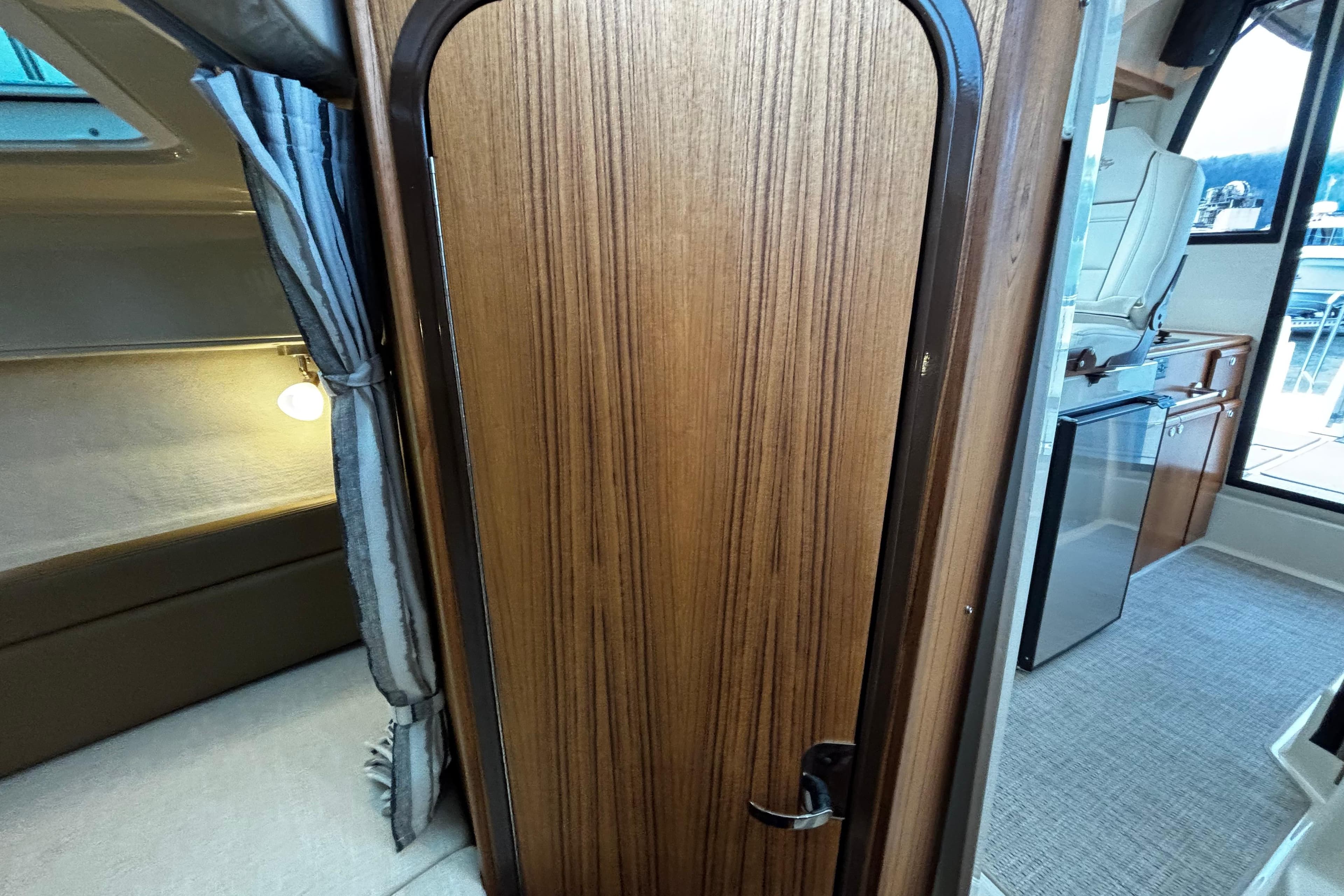 Interior of 2026 Ranger Tugs R-25, featuring wood door, cozy cabin, and kitchenette.