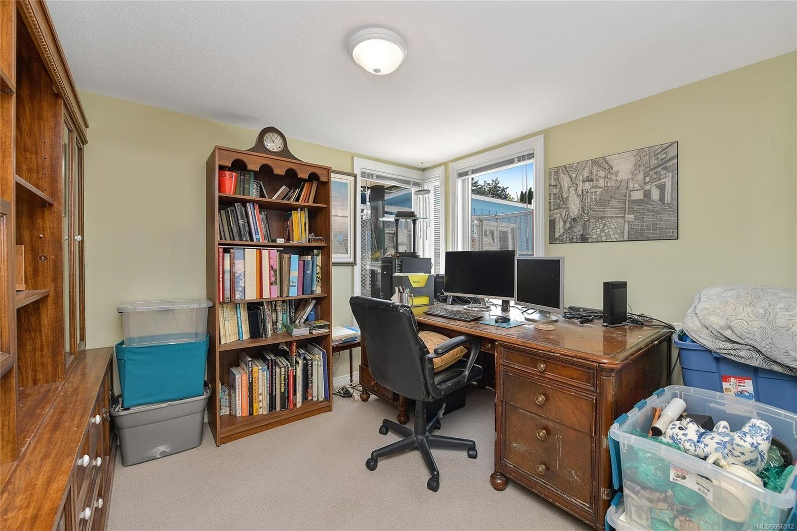 Home office with wooden desk, bookshelves, and dual monitors in a 2005 Custom Float Home.