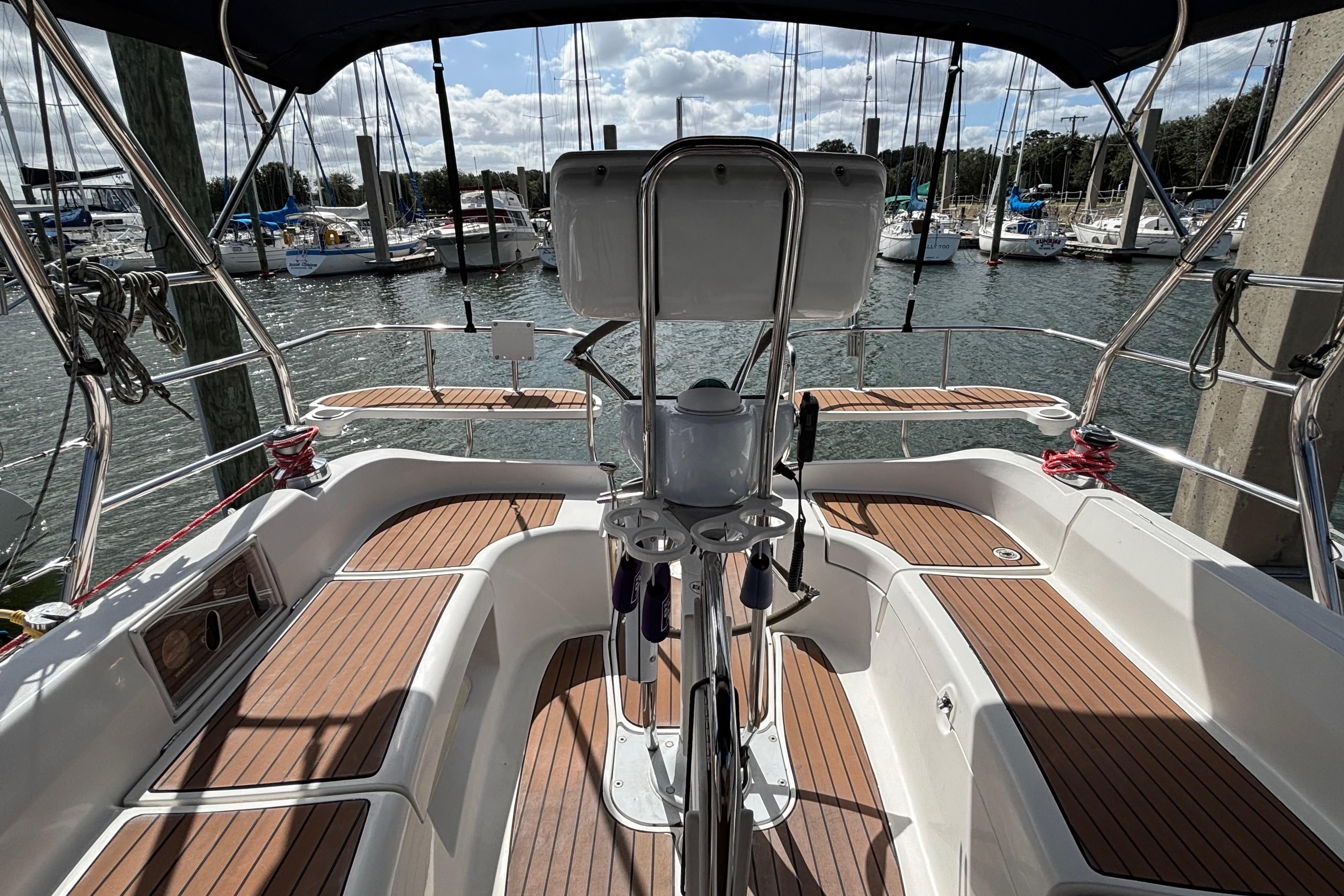 Cockpit of 2006 Hunter 38 sailboat with wooden deck, docked at marina.