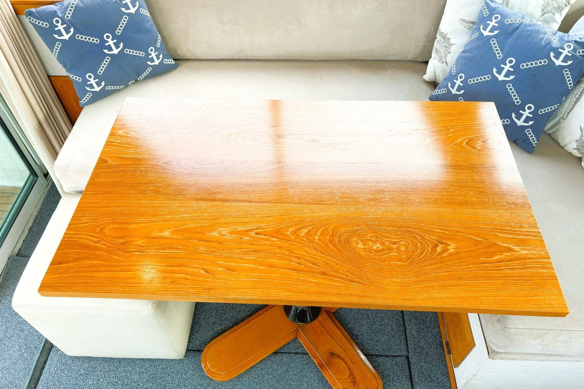 1980 Tollycraft 34 Sedan interior with wooden table and nautical-themed cushions.