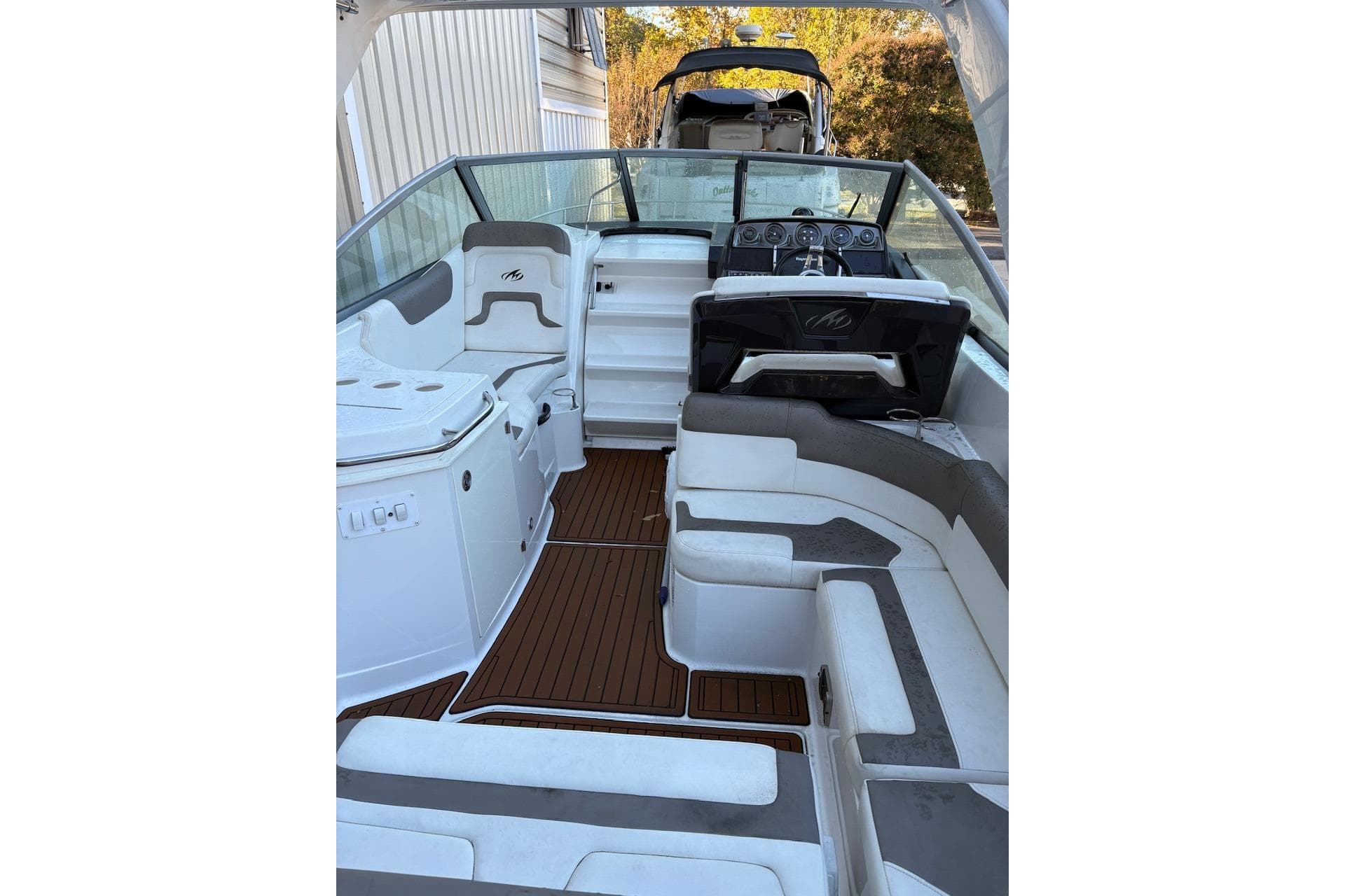 2016 Monterey 275 Sport Yacht interior with white and gray seating, wood flooring, and helm.
