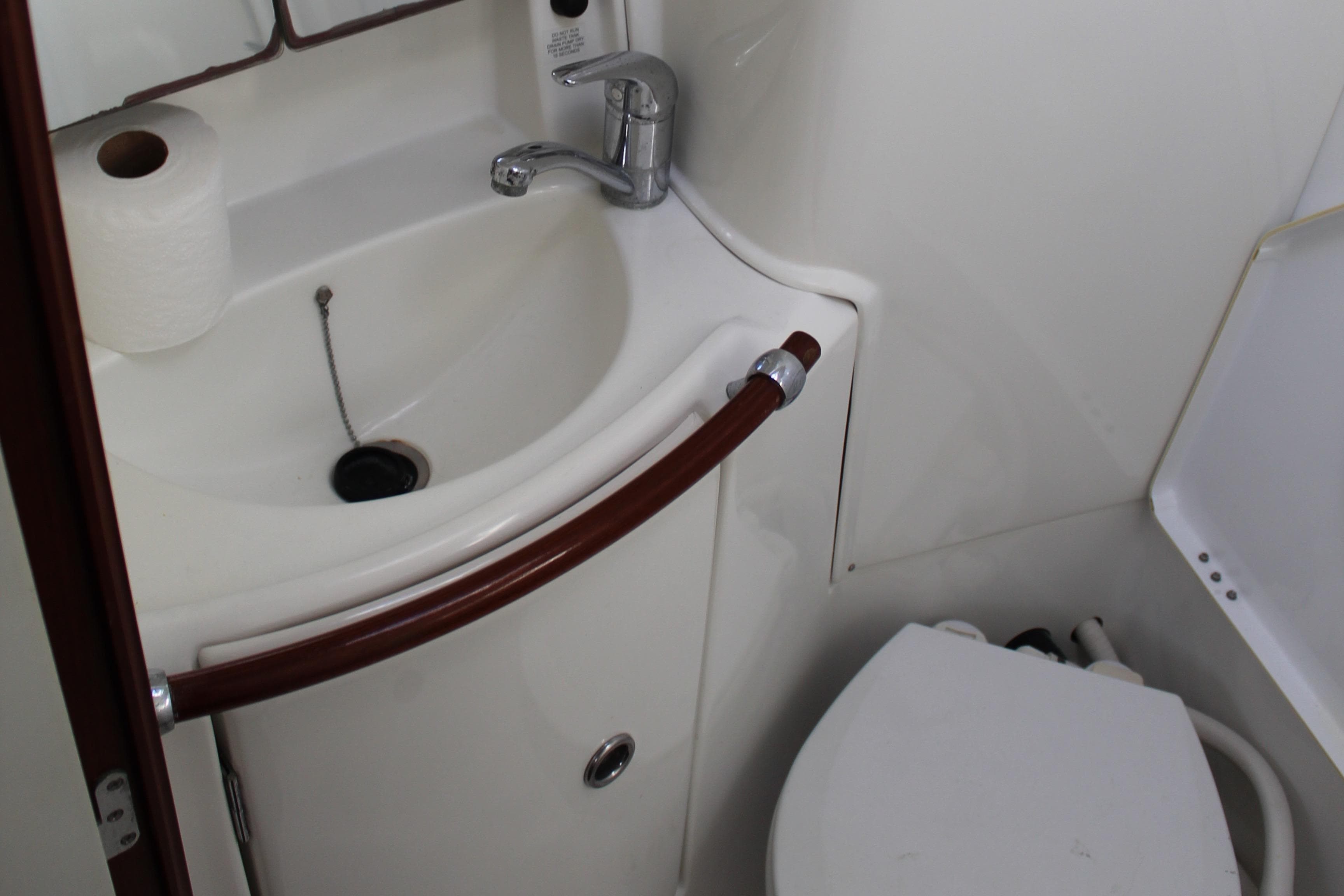 Compact bathroom in a 2004 Beneteau Oceanis Clipper 423 yacht, featuring a sink and toilet.
