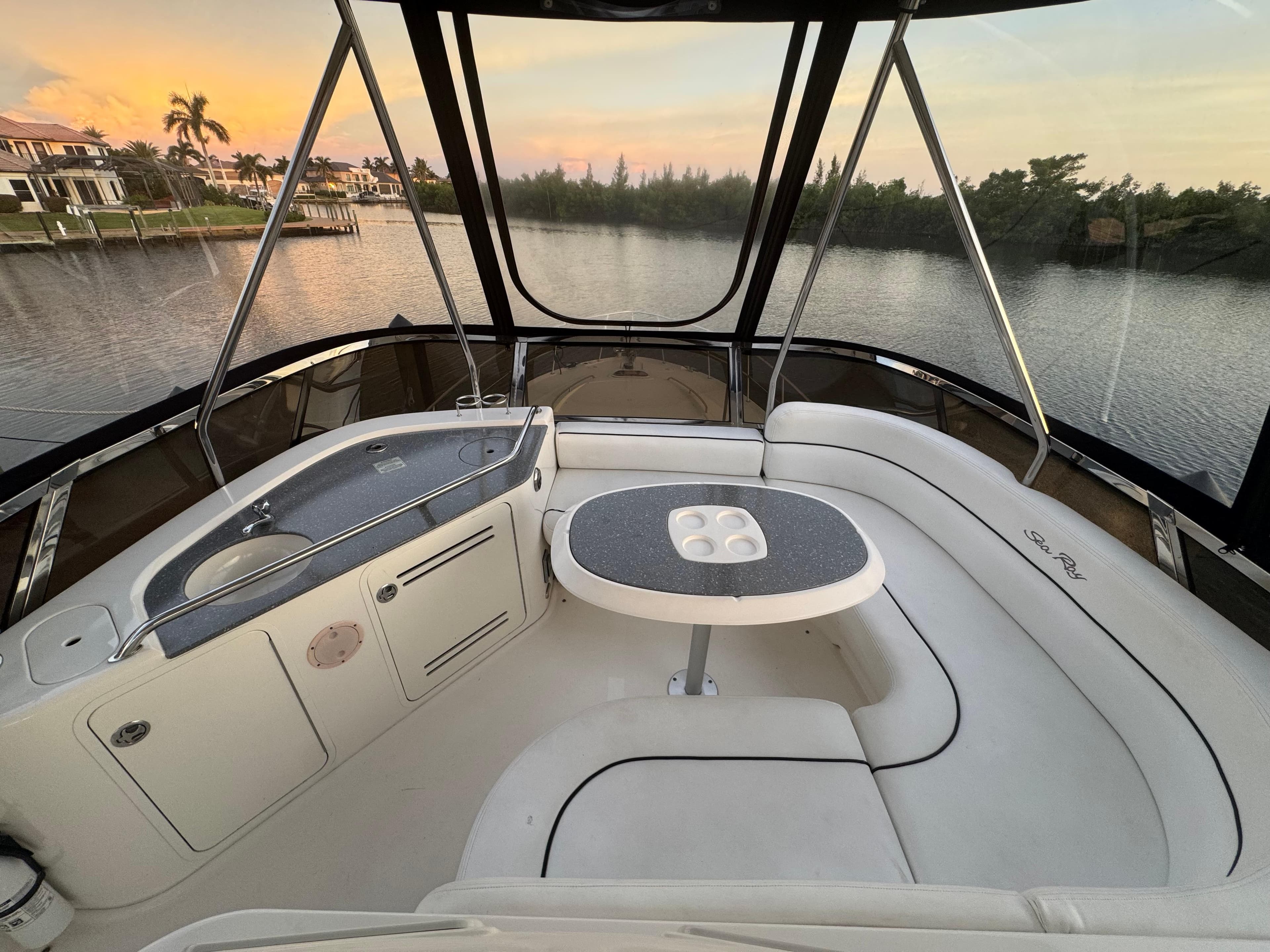 2007 Sea Ray 52 Sedan Bridge interior with seating and table, overlooking serene waterfront.