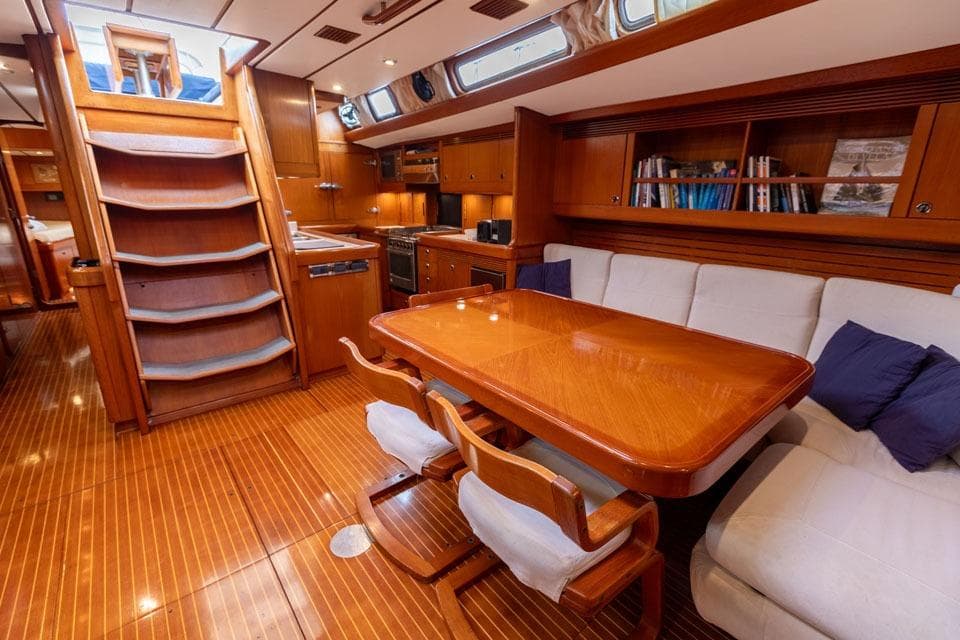 Luxurious interior of 1992 Nautor Swan 68 yacht with wooden dining area and cozy seating.