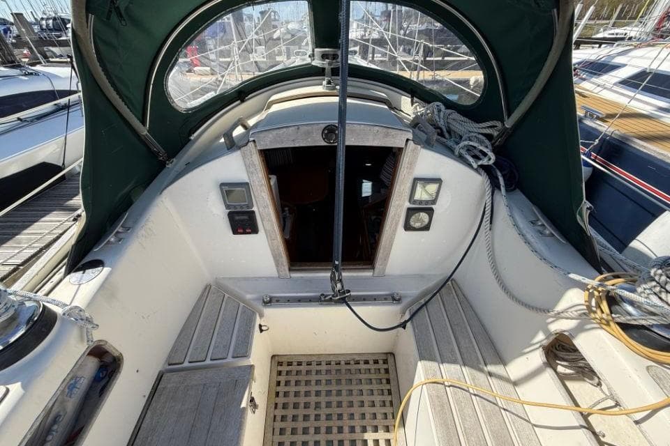 Cockpit of 1980 Rival 34 sailboat with green canopy and wooden flooring.