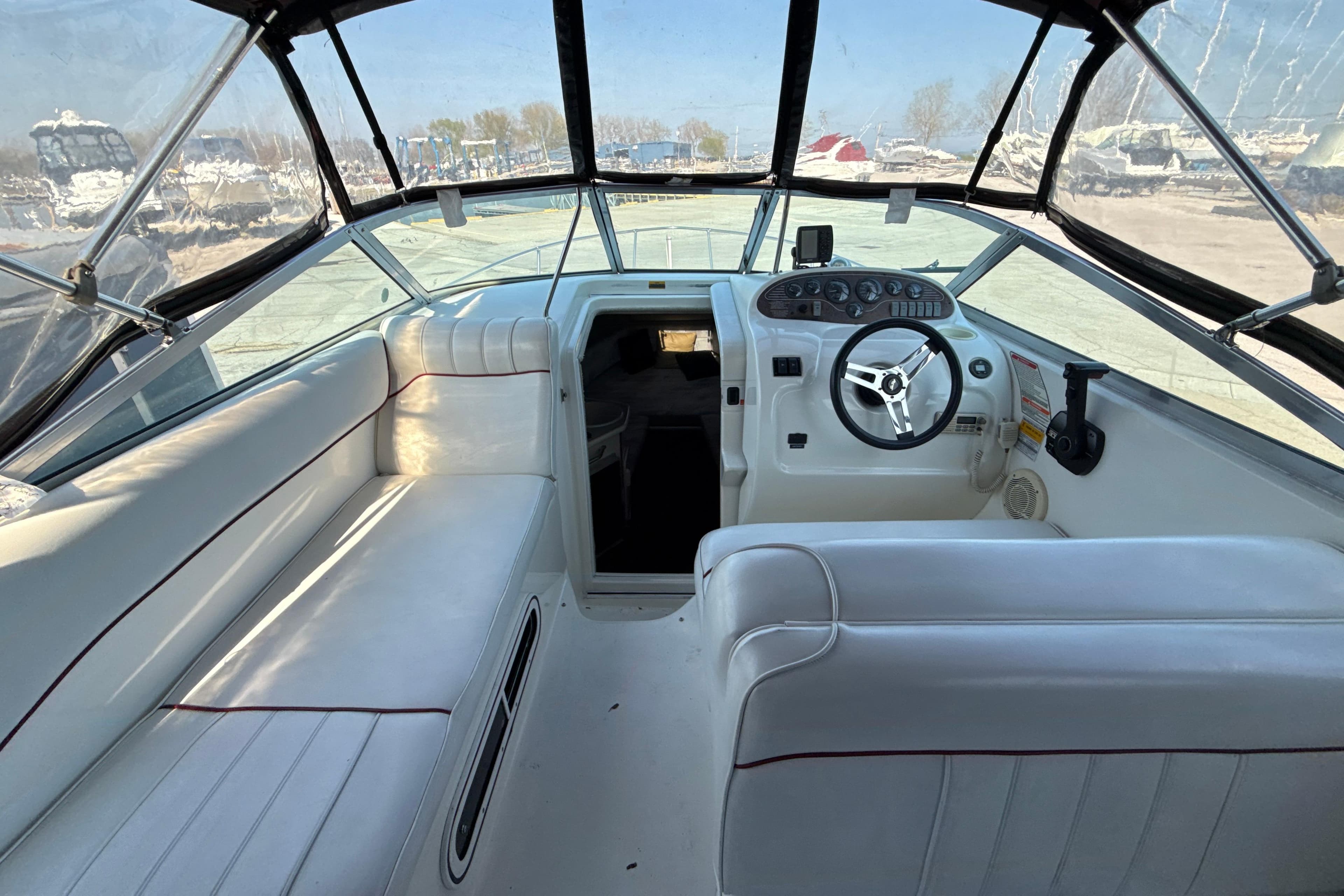 1996 Sea Ray 240 Sundancer boat interior with white seating and steering console.