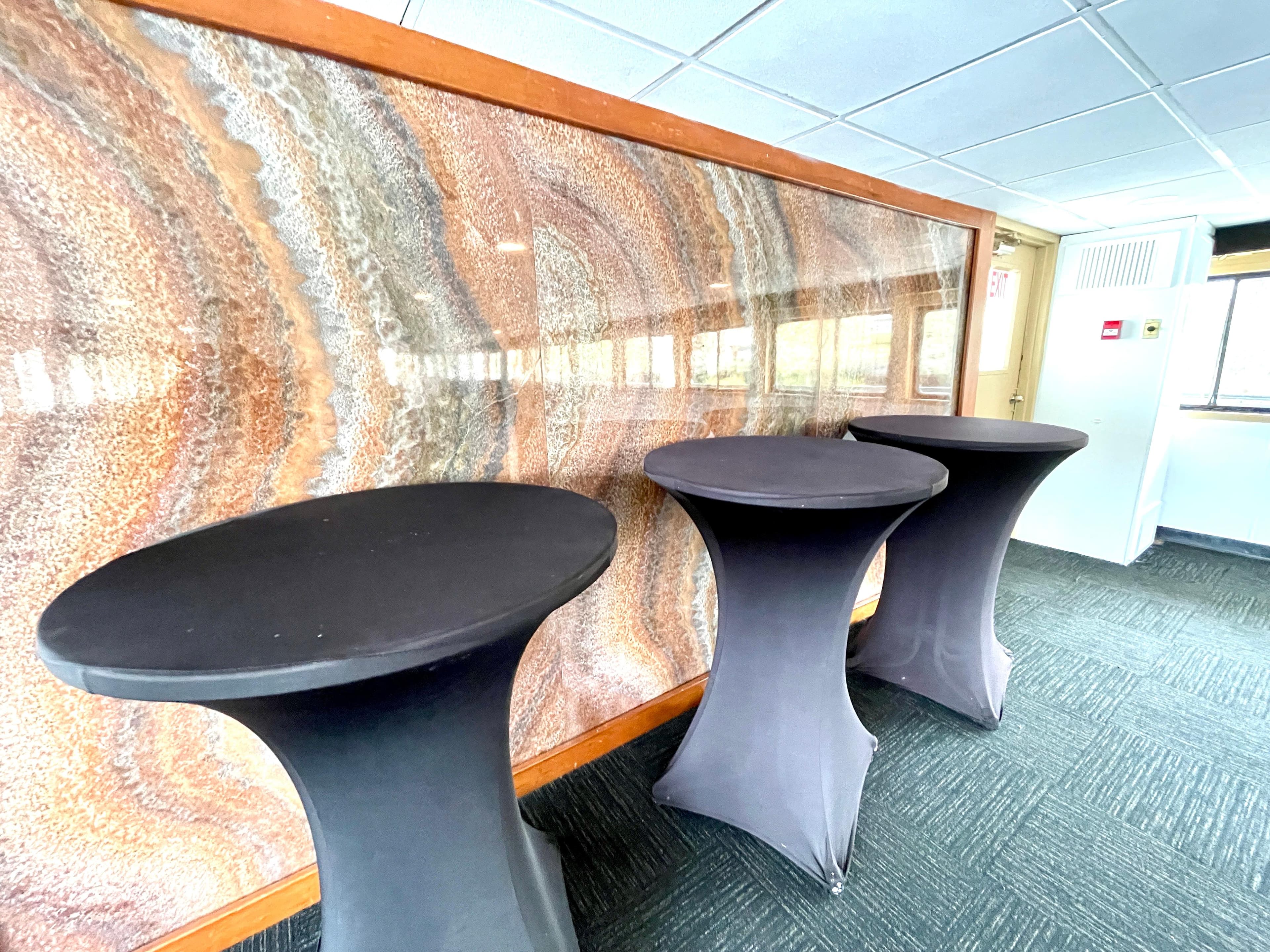 Three black cocktail tables with covers in a modern interior setting.