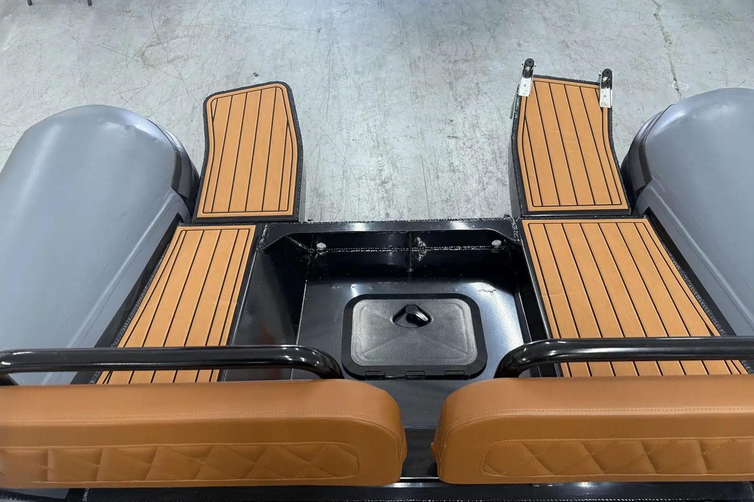 Manufacturer Provided Image: 2025 East Marine 700 boat interior with brown cushioned seats and wooden flooring.