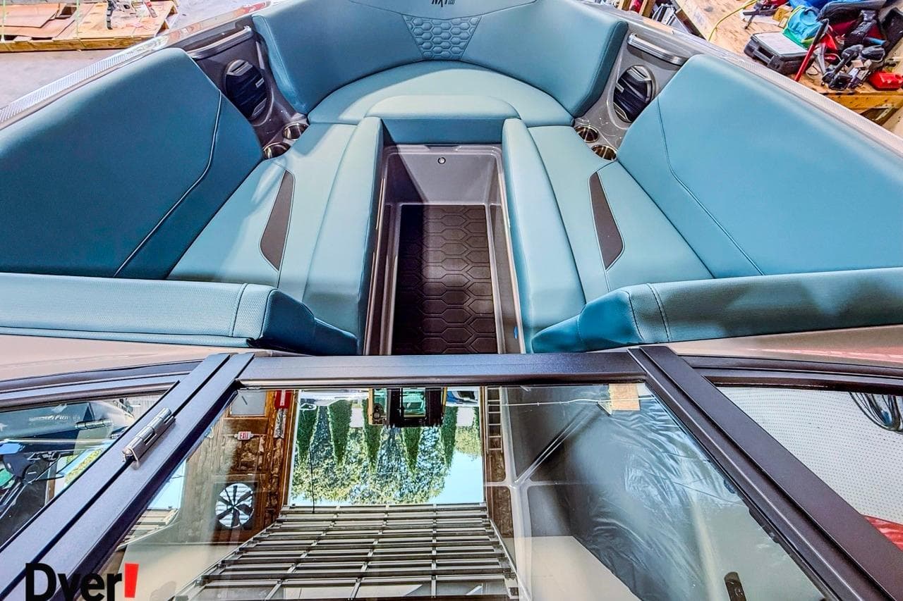 2026 MasterCraft NXT23 boat interior with blue seating and storage compartment.