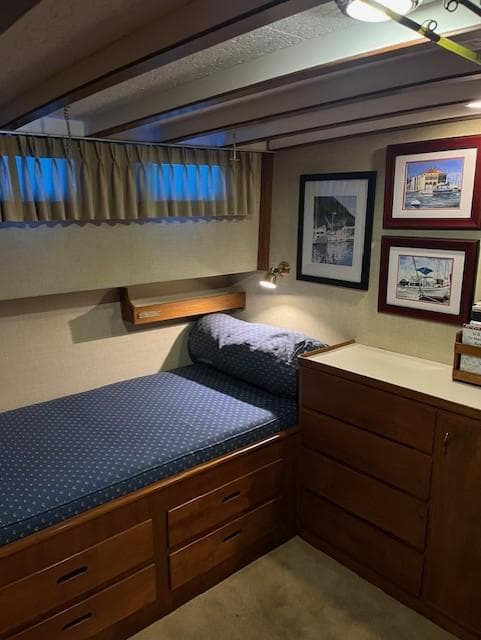 Cozy cabin interior of 1972 DeFever 38 Passagemaker with bed, wooden drawers, and framed artwork.