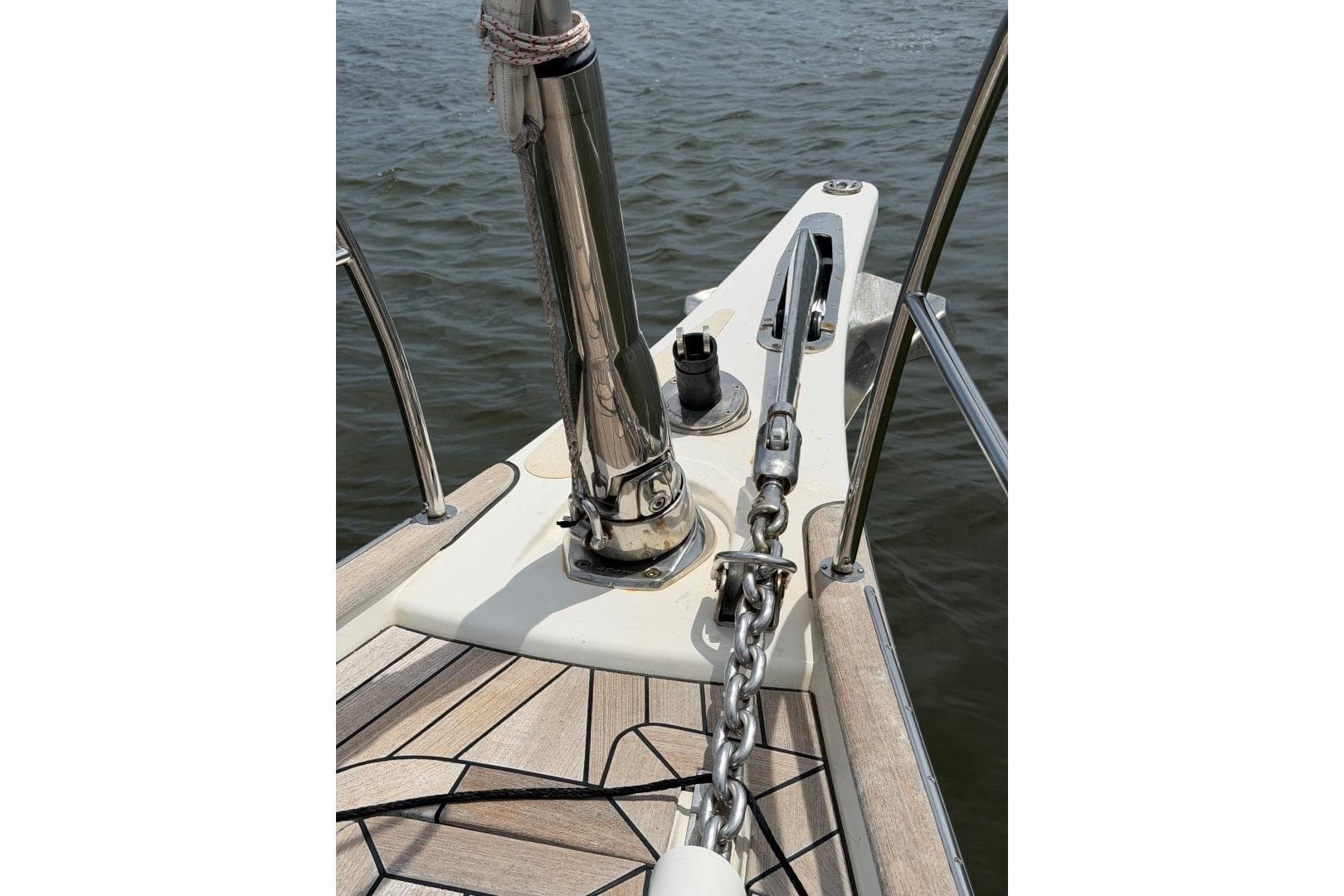Bow of 2023 Hallberg-Rassy 57 yacht with anchor chain and teak deck.