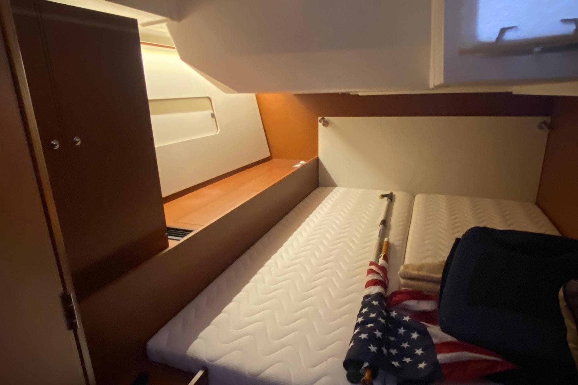 Interior cabin of 2019 Beneteau Oceanis 51.1 yacht with bed and American flag.