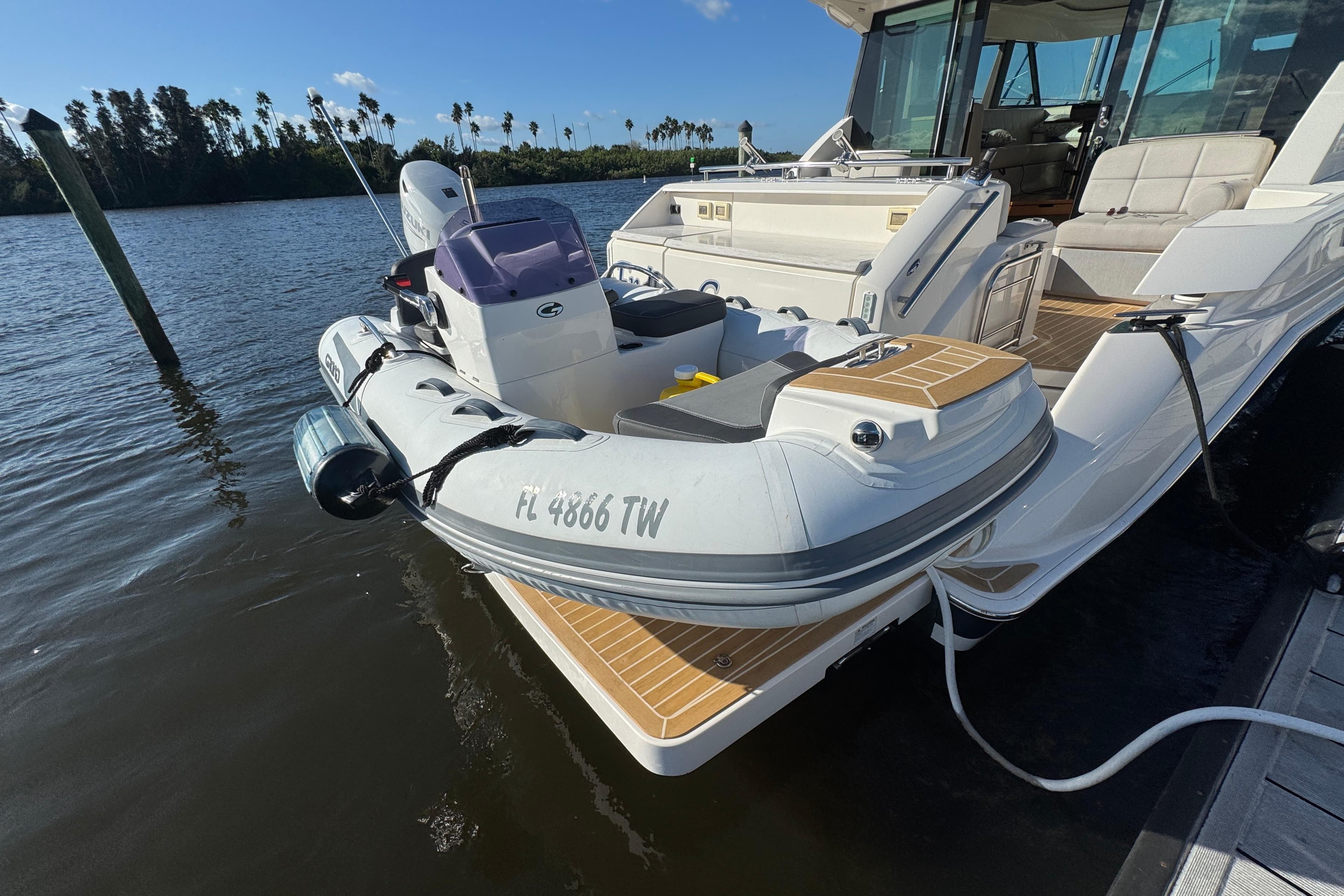 2016 Tiara Yachts C44 Coupe docked with inflatable boat on water.