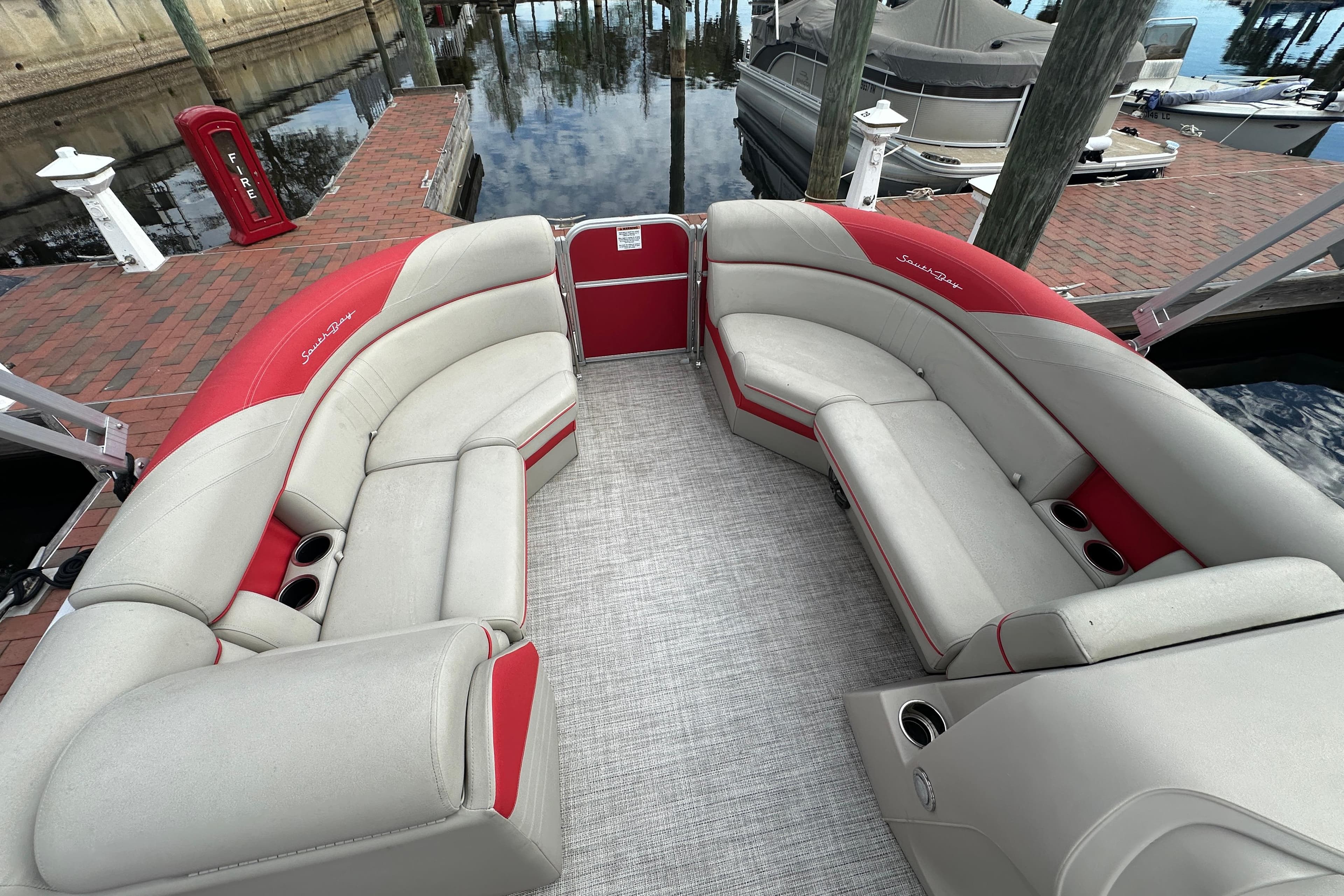 2022 South Bay Pontoons 24 LE Series Tri Hull with red and beige seating at dock.