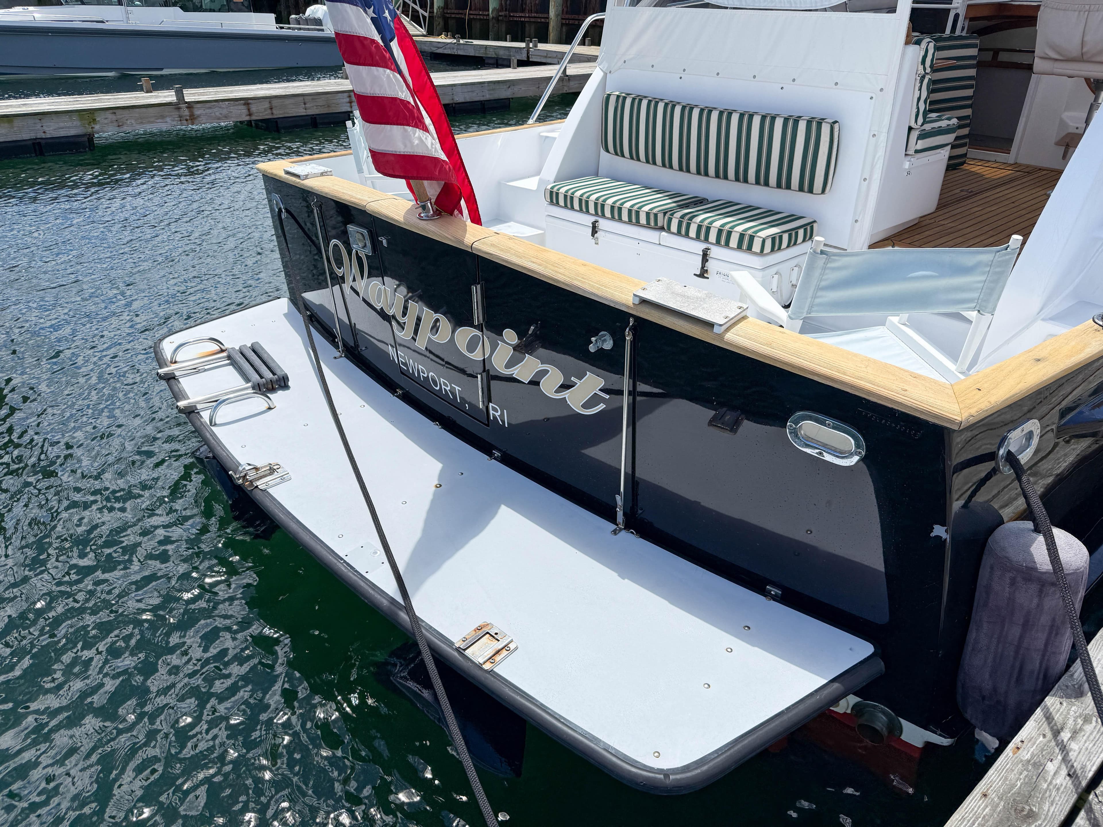 2002 Legacy 34 Express boat docked, featuring striped seating and American flag.