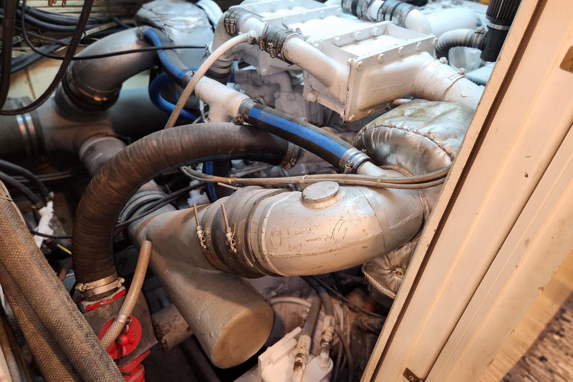 Engine room of a 1978 Hatteras 53 Motor Yacht with visible pipes and components.