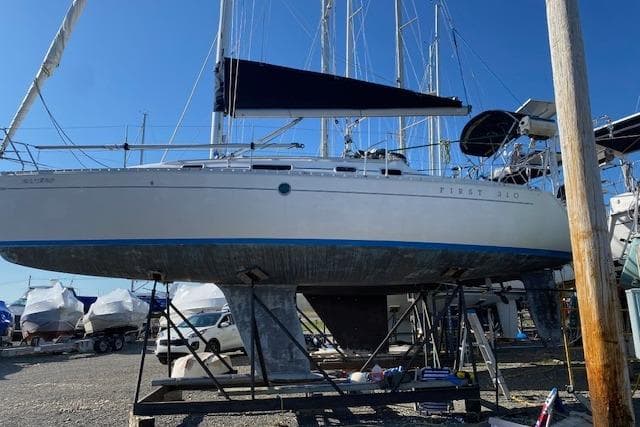 1992 Beneteau First 310 sailboat on dry dock, side view with blue trim.