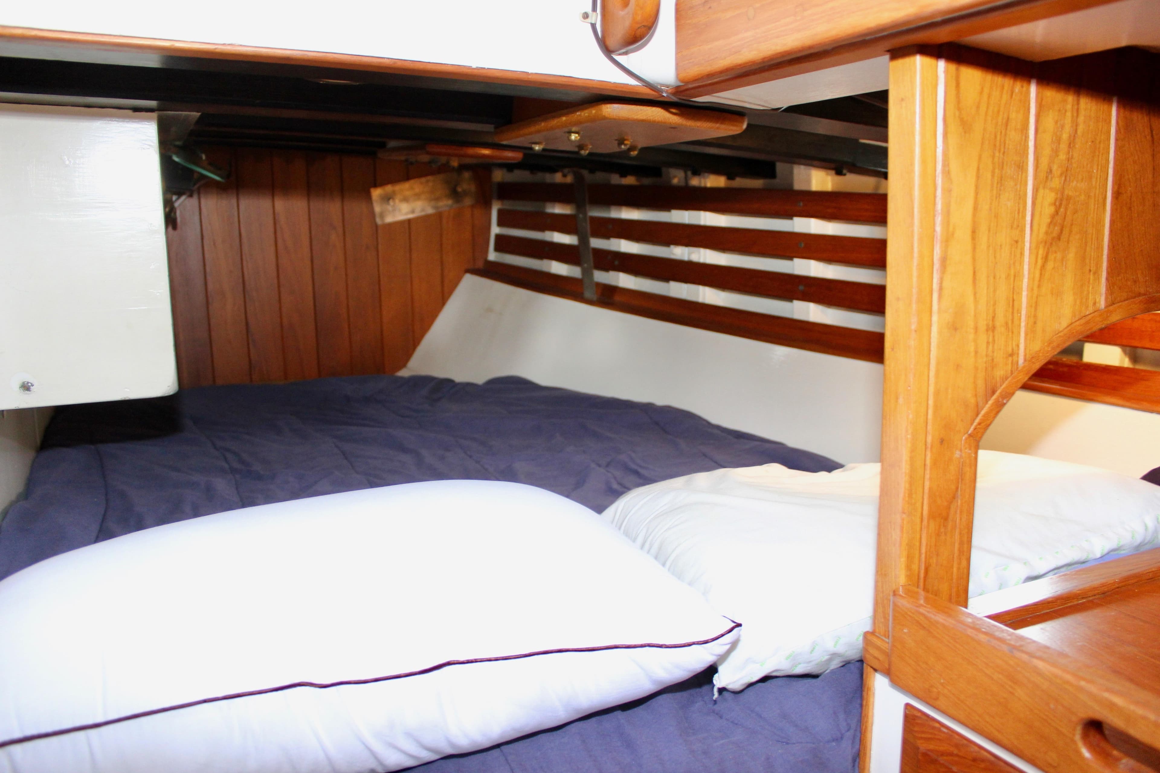 Cozy cabin interior of 1975 William Garden Porpoise sailboat with wooden paneling and bedding.