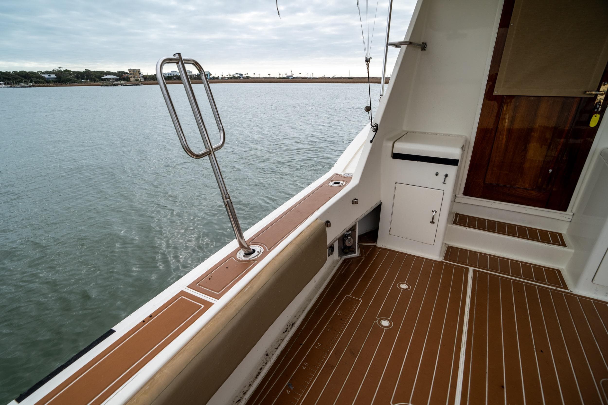 1984 Hatteras 52 Convertible yacht deck with wooden flooring and water view.