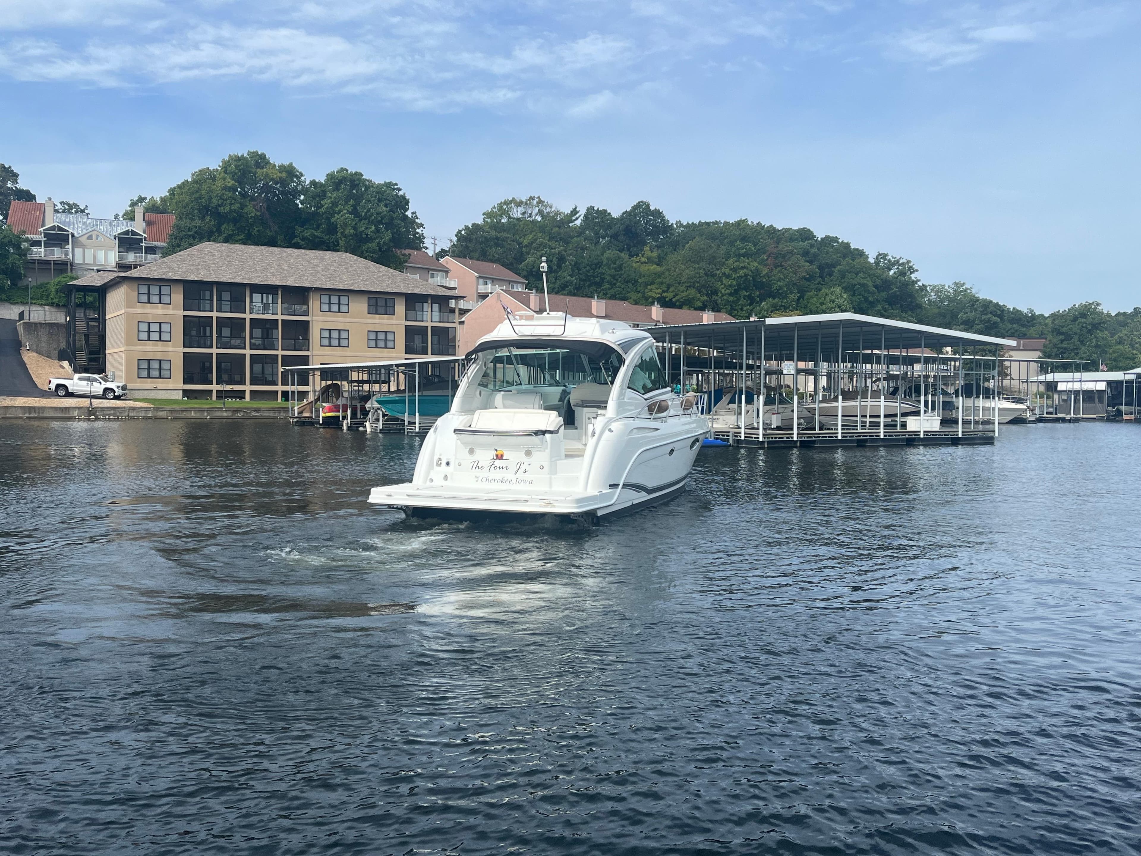 2014 Formula 45 Yacht cruising near lakeside buildings and docks.