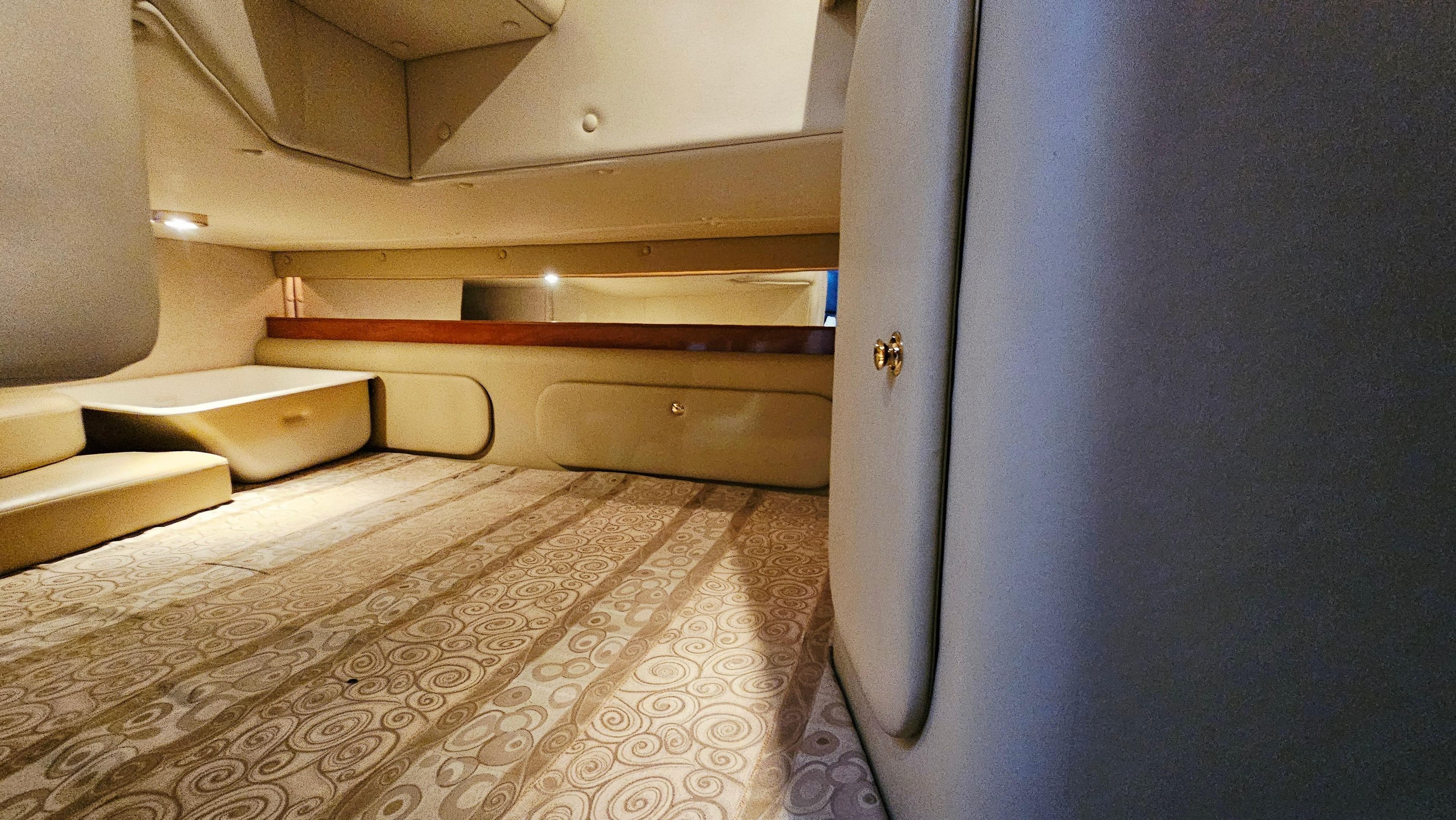 2005 Rinker 300 Express Cruiser interior cabin with beige upholstery and patterned flooring.