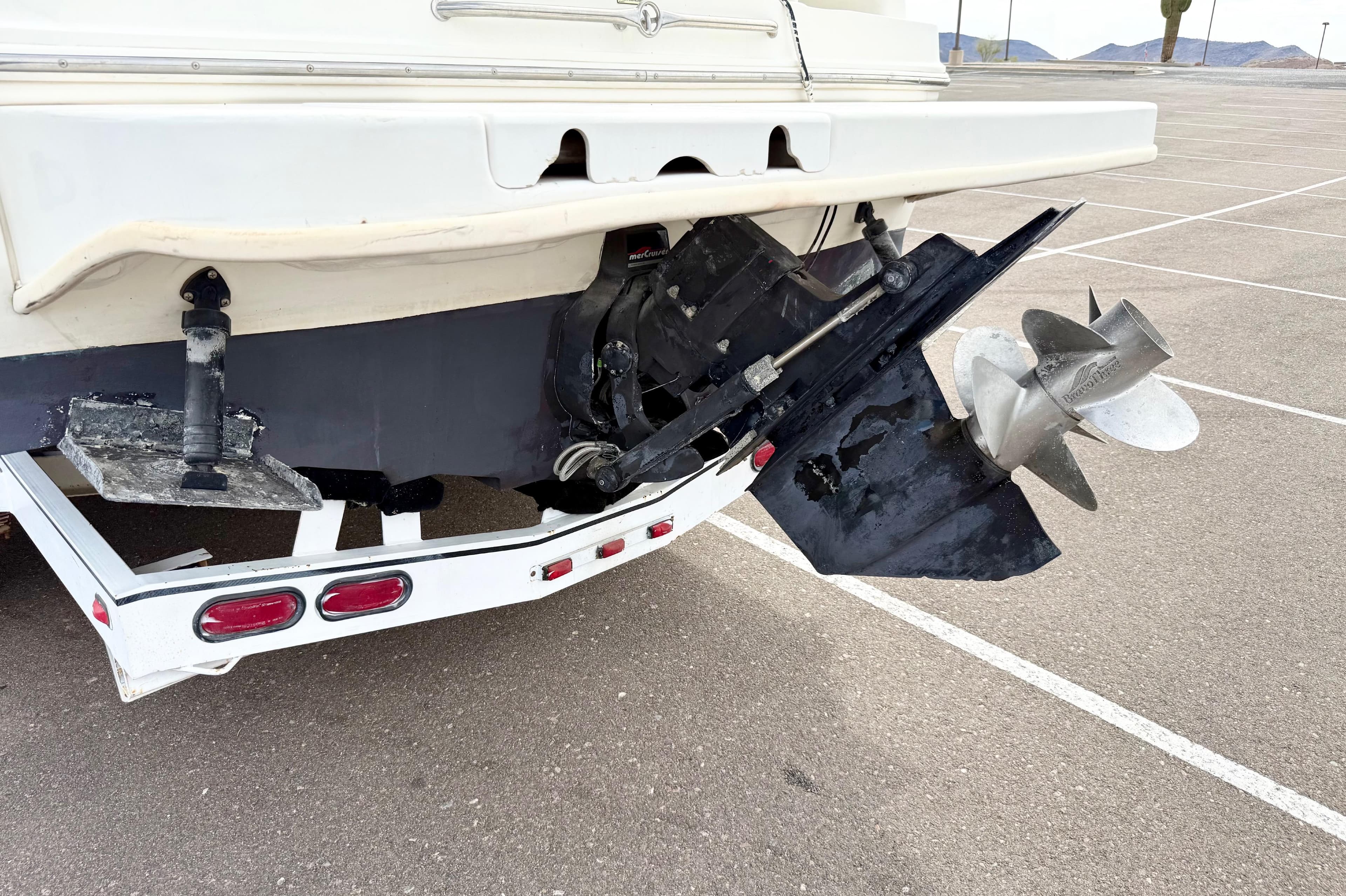 1999 Sea Ray Sundancer 260 boat stern with propeller and trailer in parking lot.