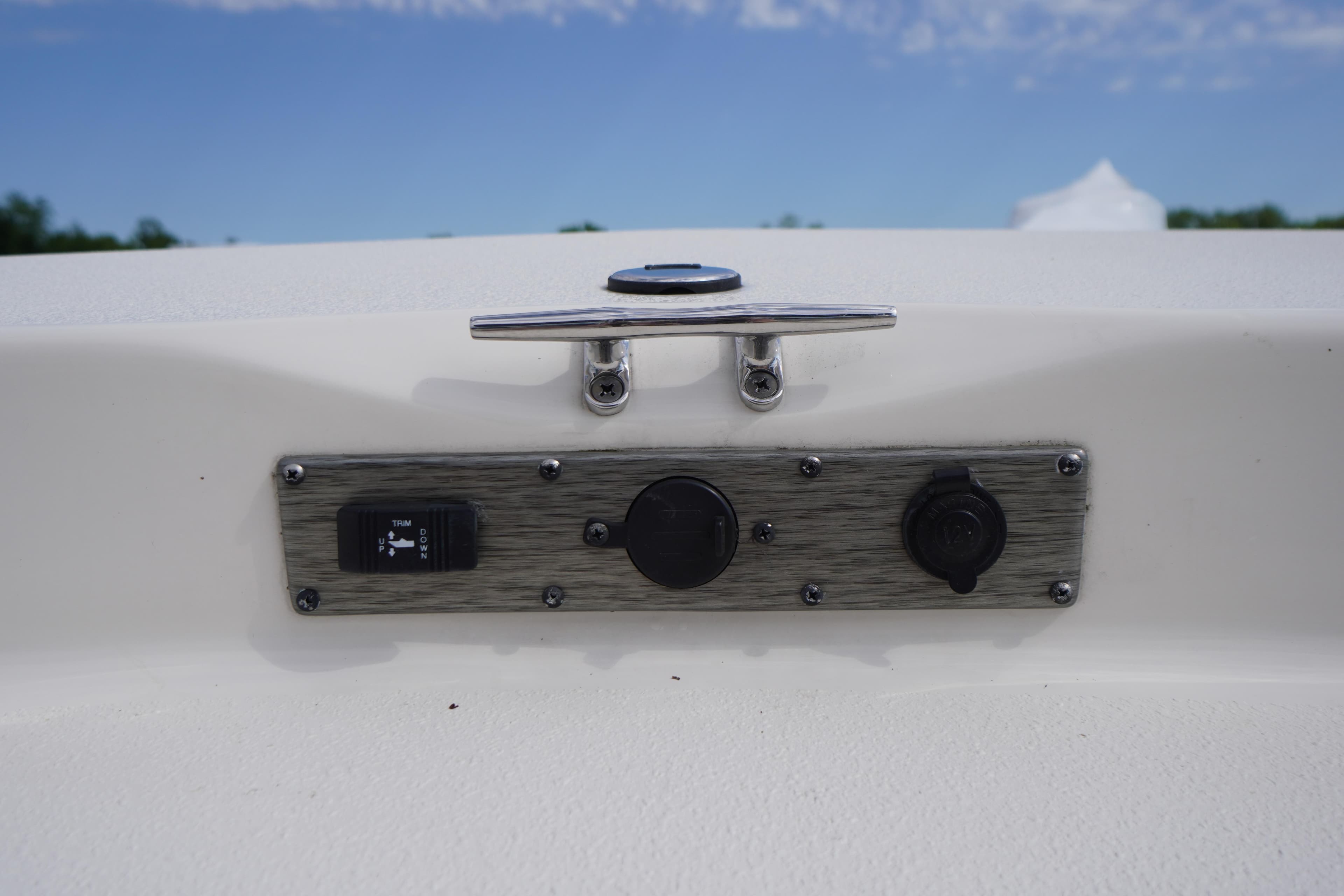 2024 Carolina Skiff 182 boat control panel with switches and cleat against blue sky.
