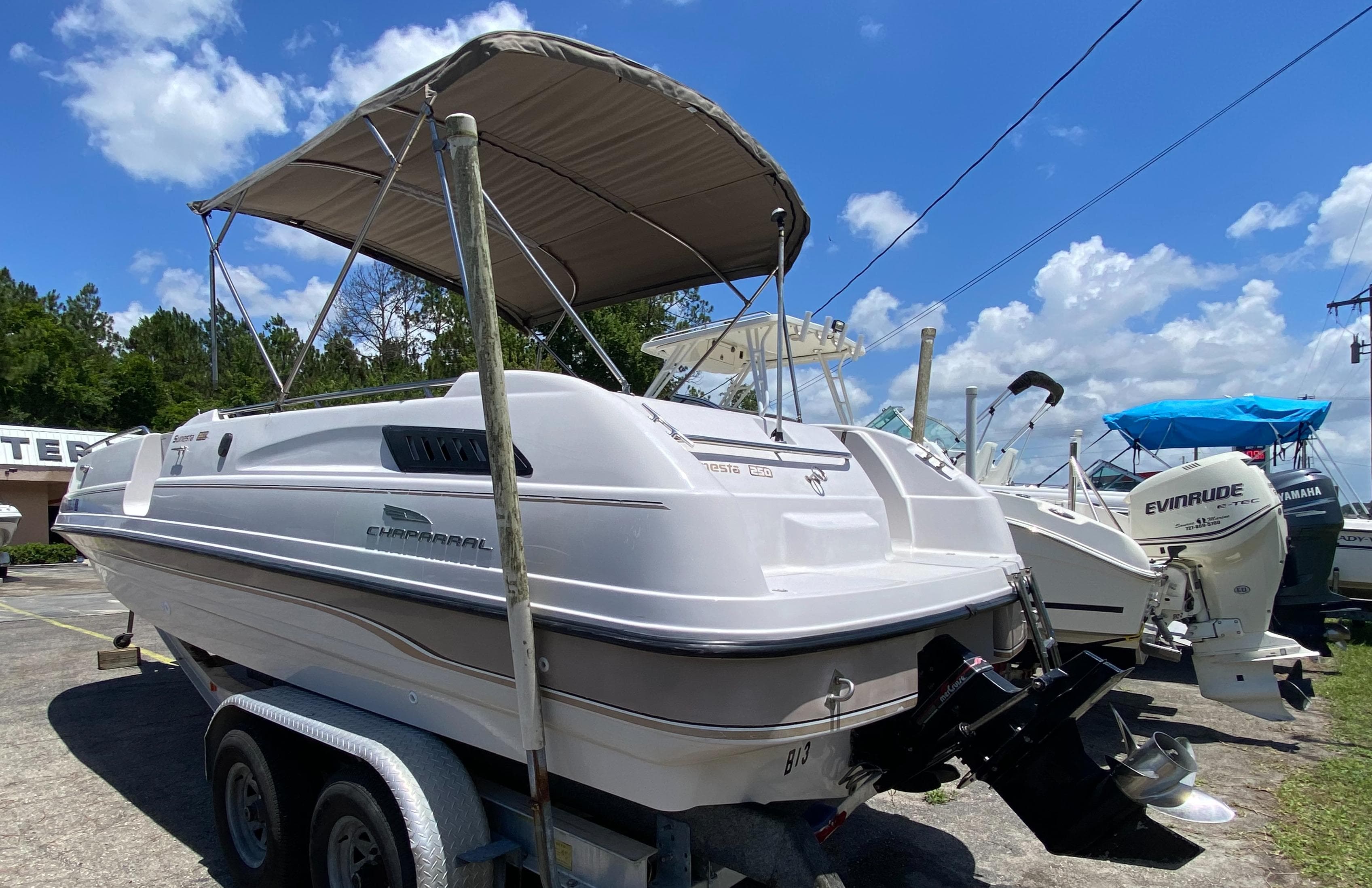 1997 Chaparral 250 Sunseta boat on trailer, with canopy, parked outdoors.
