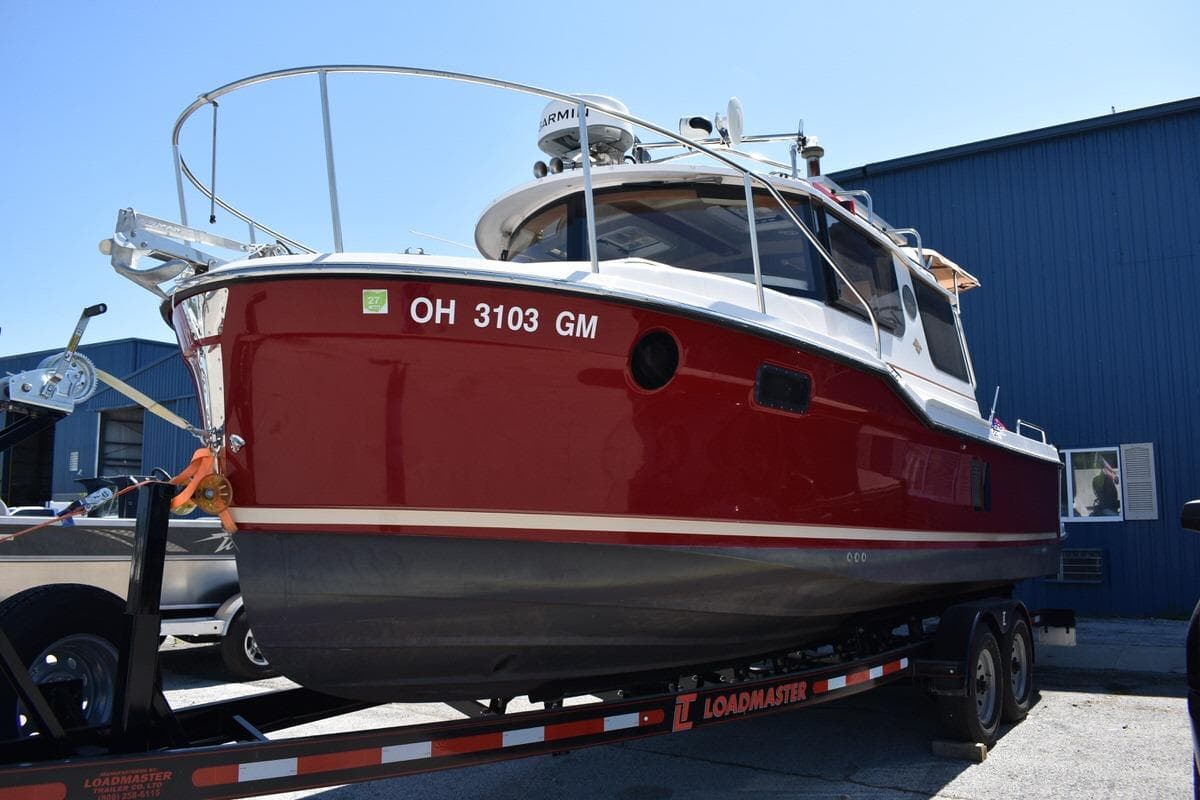 2024 Ranger Tugs R-25 boat on trailer, red hull, parked outdoors.