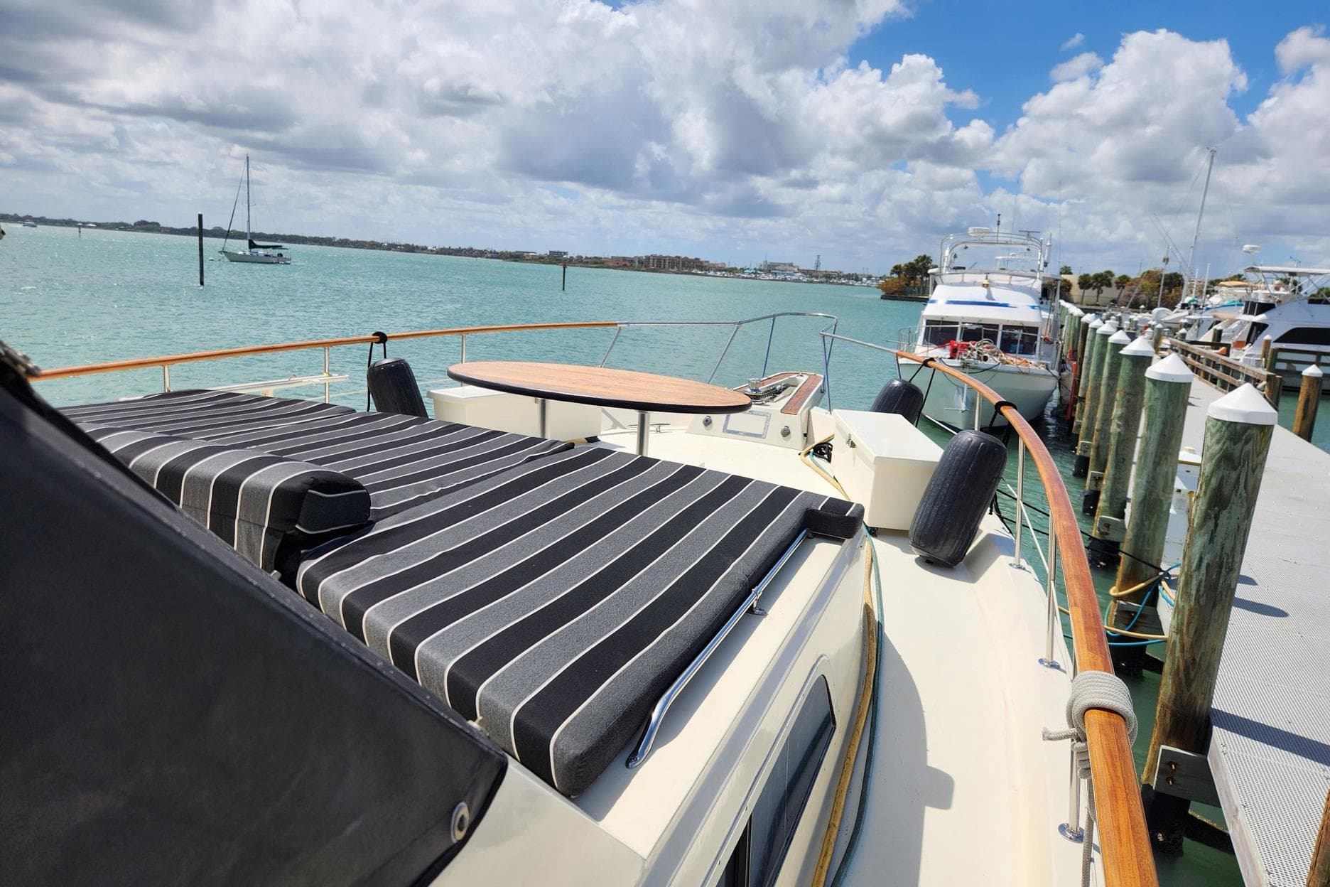 1978 Hatteras 53 Motor Yacht docked, featuring striped sunbathing area and scenic waterfront view.