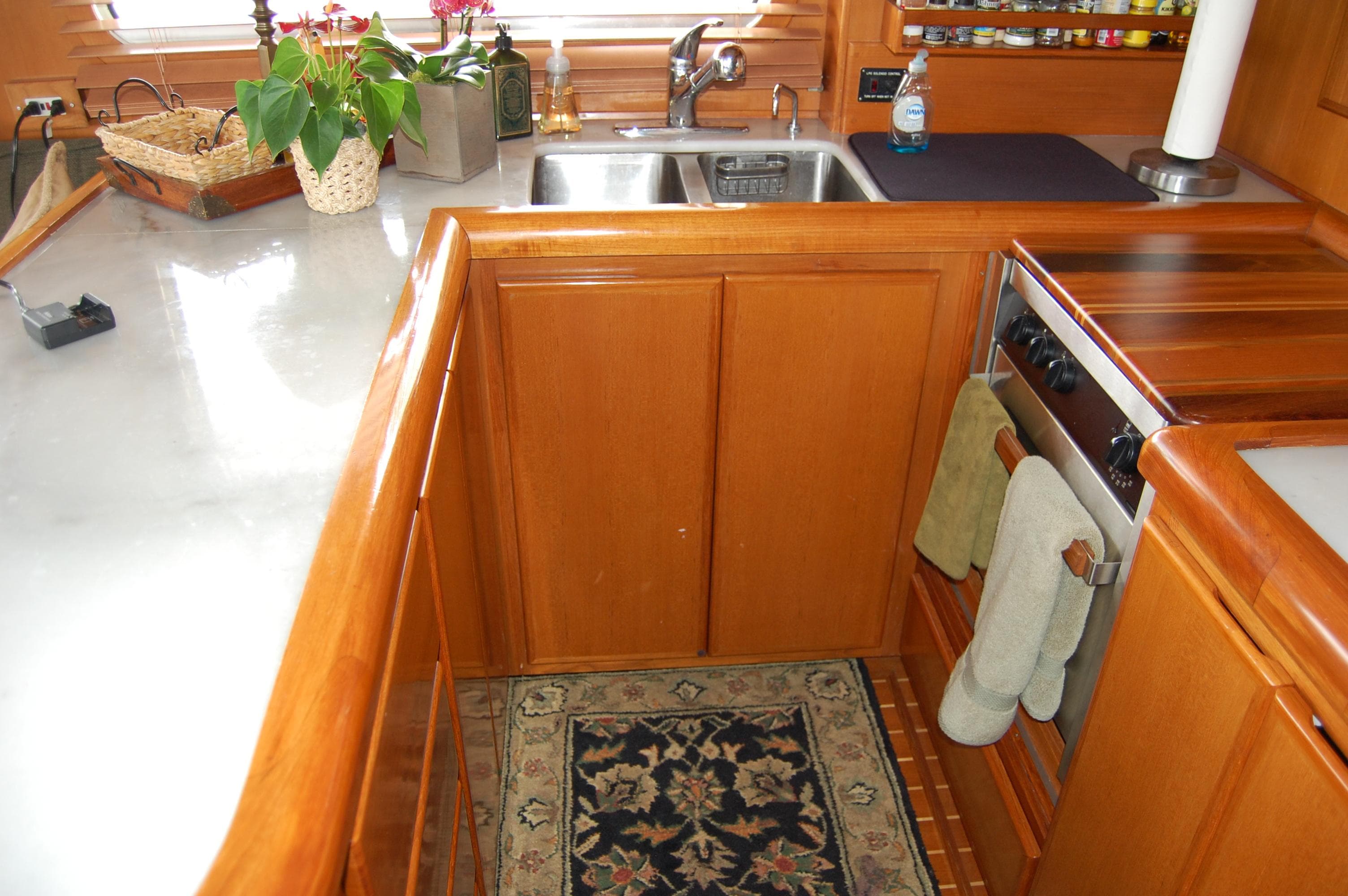 2002 Eagle Pilothouse kitchen with wooden cabinetry, sink, stove, and decorative rug.