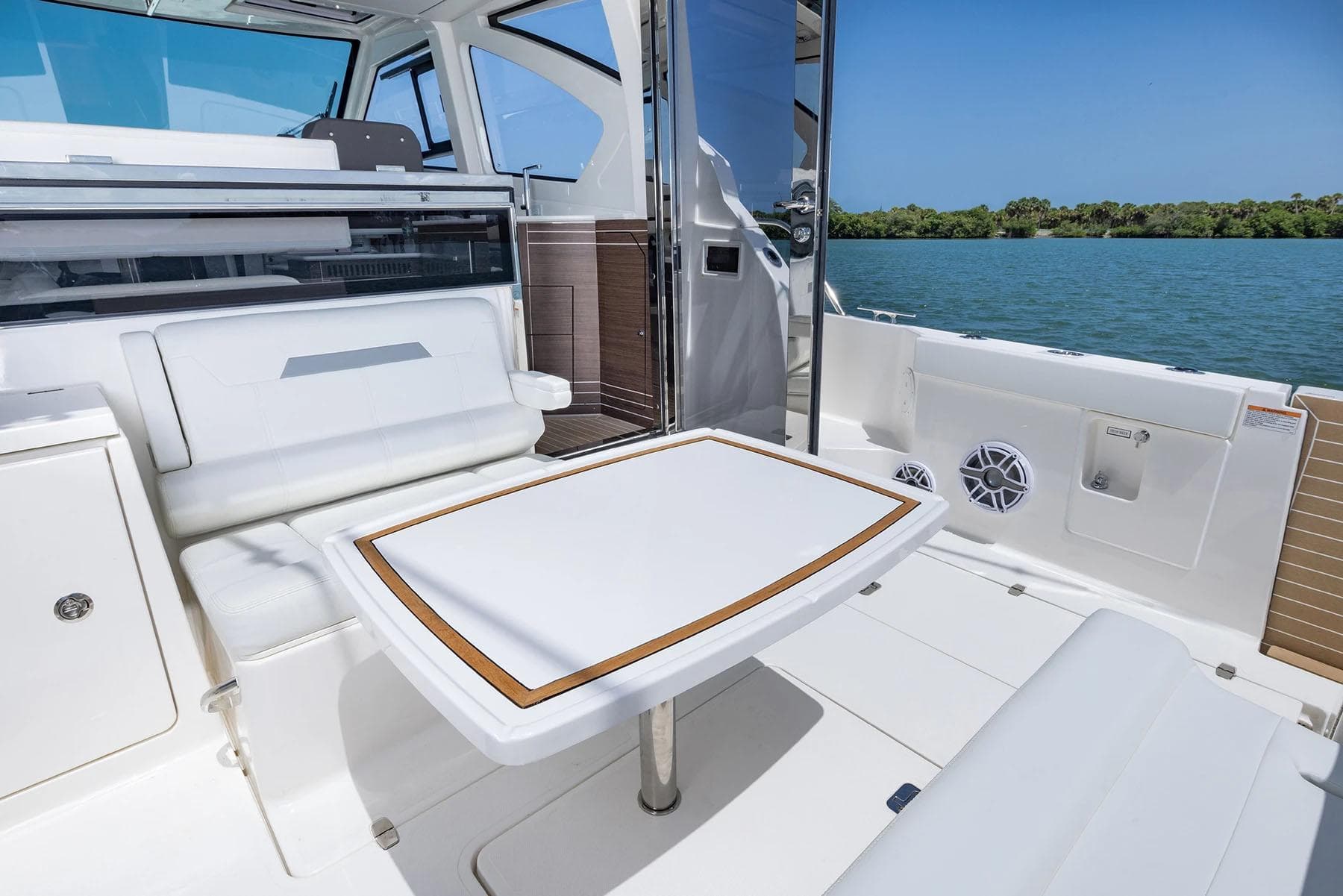 Manufacturer Provided Image: 2025 Pursuit OS 445 Offshore boat interior with seating and table, overlooking serene water.