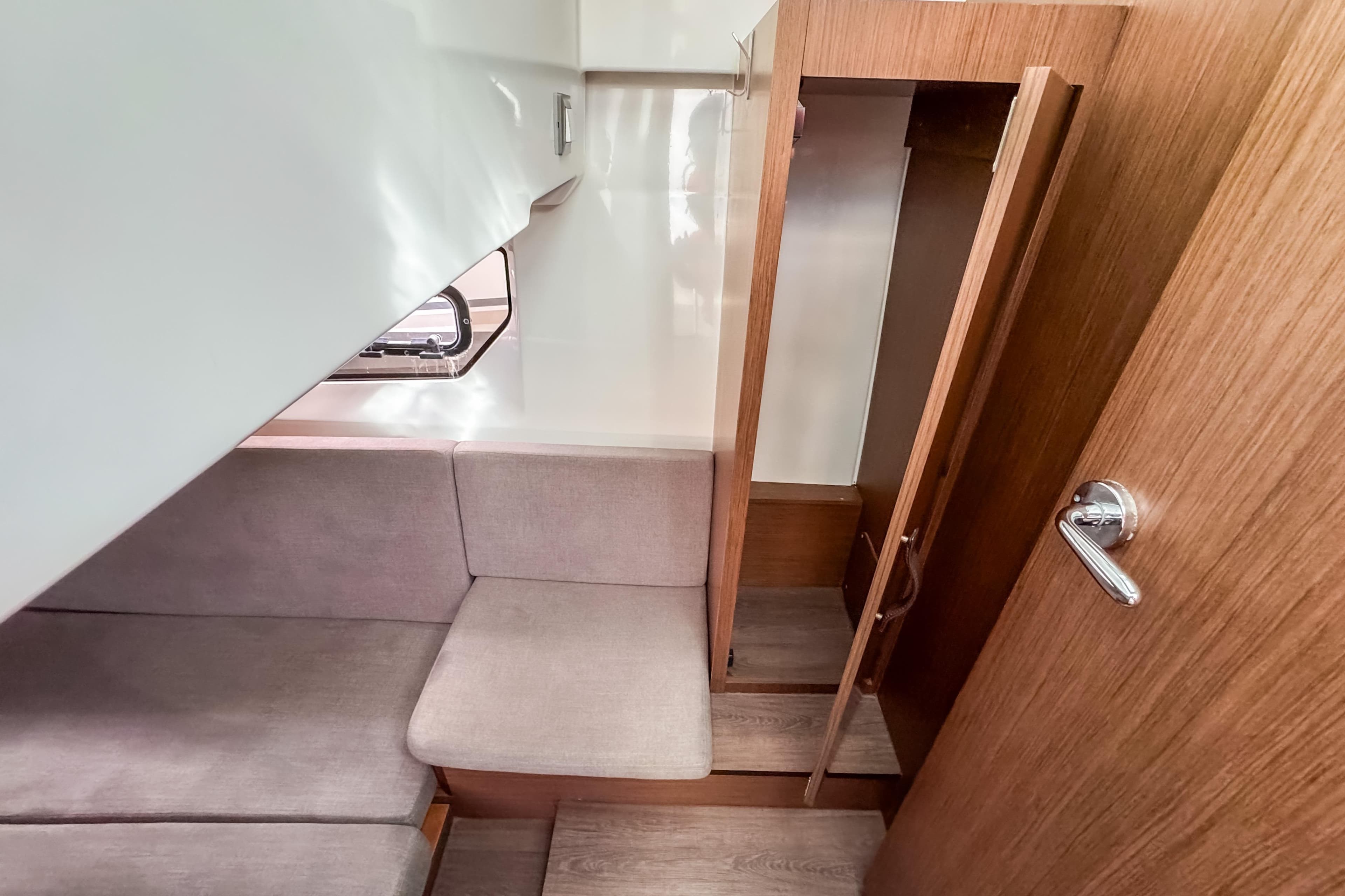2024 Beneteau Antares 11 cabin interior with wooden finish and seating area.