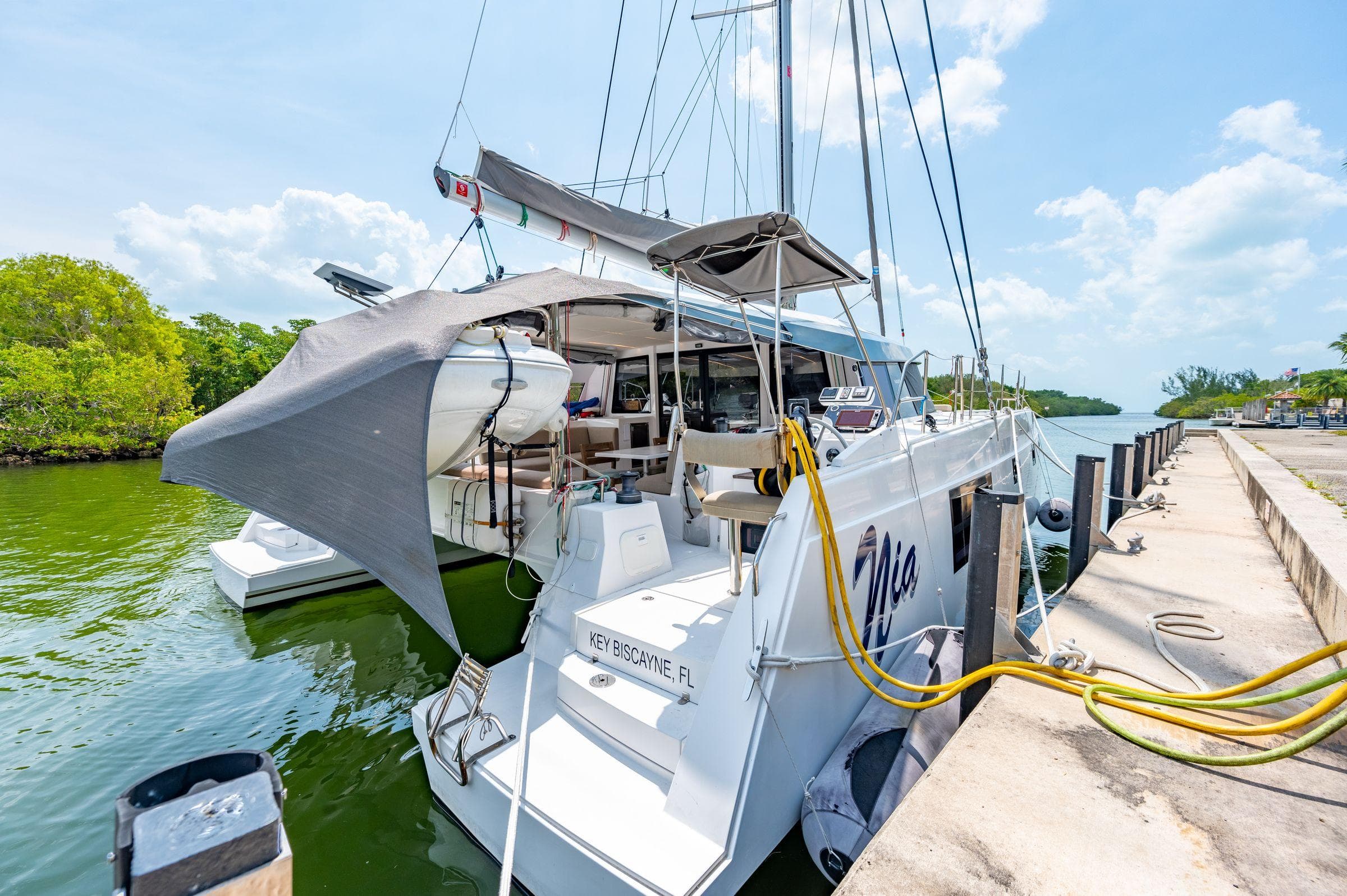 Nautitech 46 Open 2021 catamaran docked by lush greenery and clear skies.