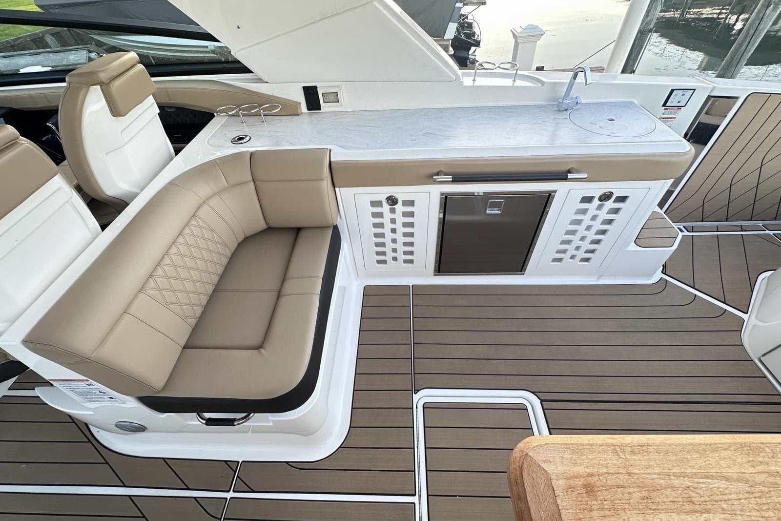 2024 Sea Ray SLX 400 boat interior with seating, kitchenette, and wood flooring.