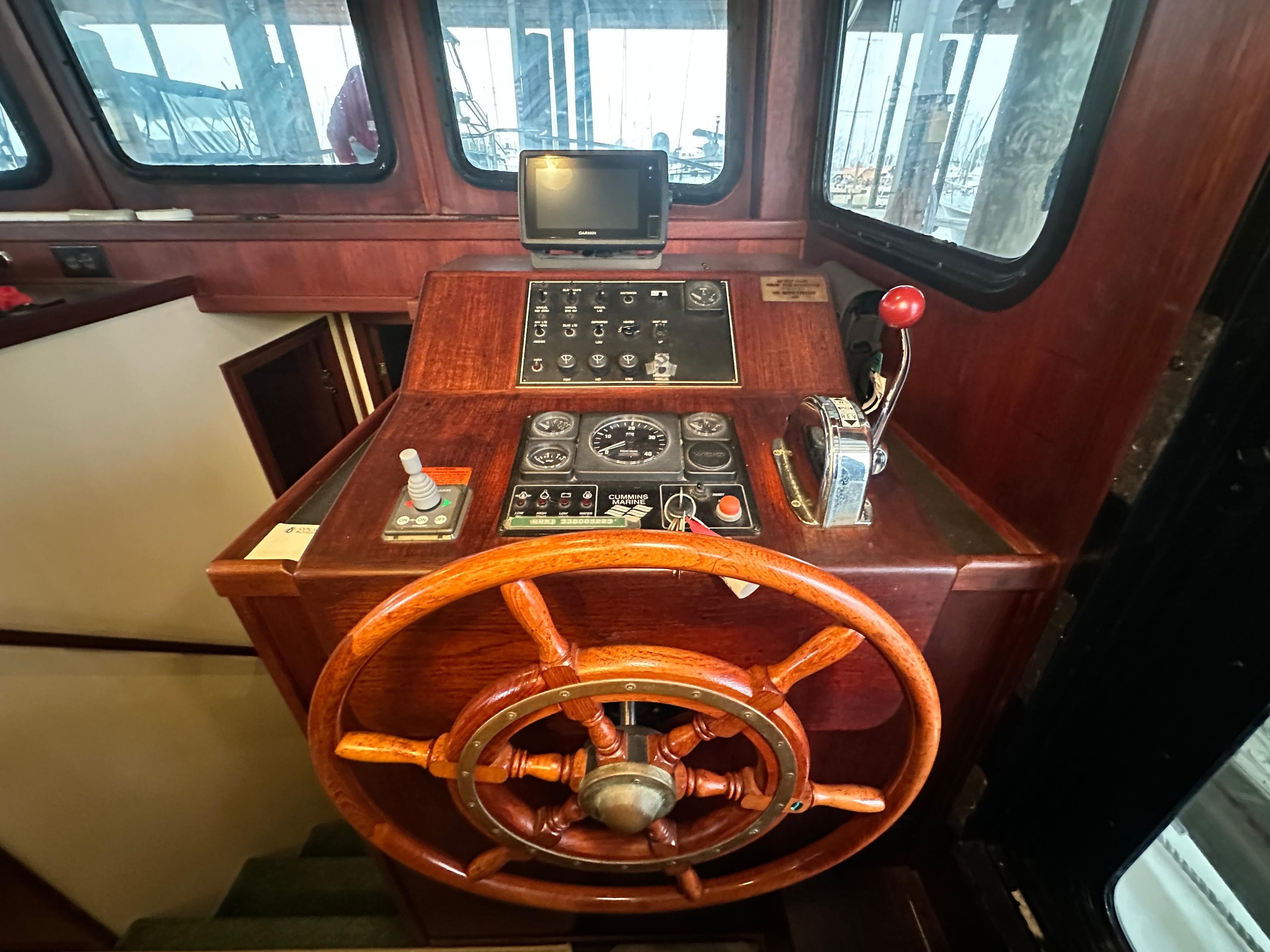 Pilothouse of 2001 Nordic Tug 37 with wooden wheel and control panel.