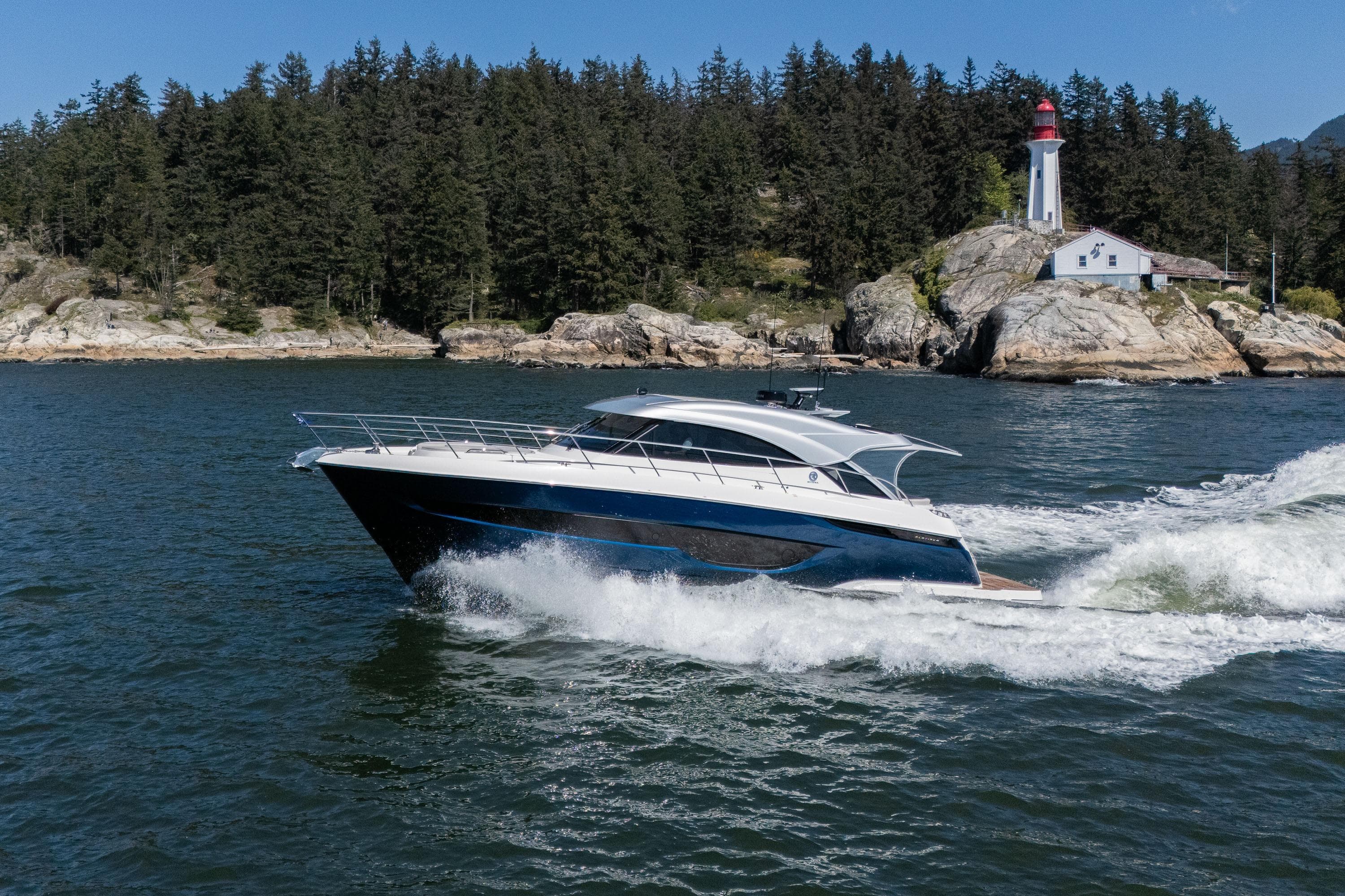 2026 Riviera 4600 Sport Yacht Platinum Edition cruising near a scenic lighthouse.