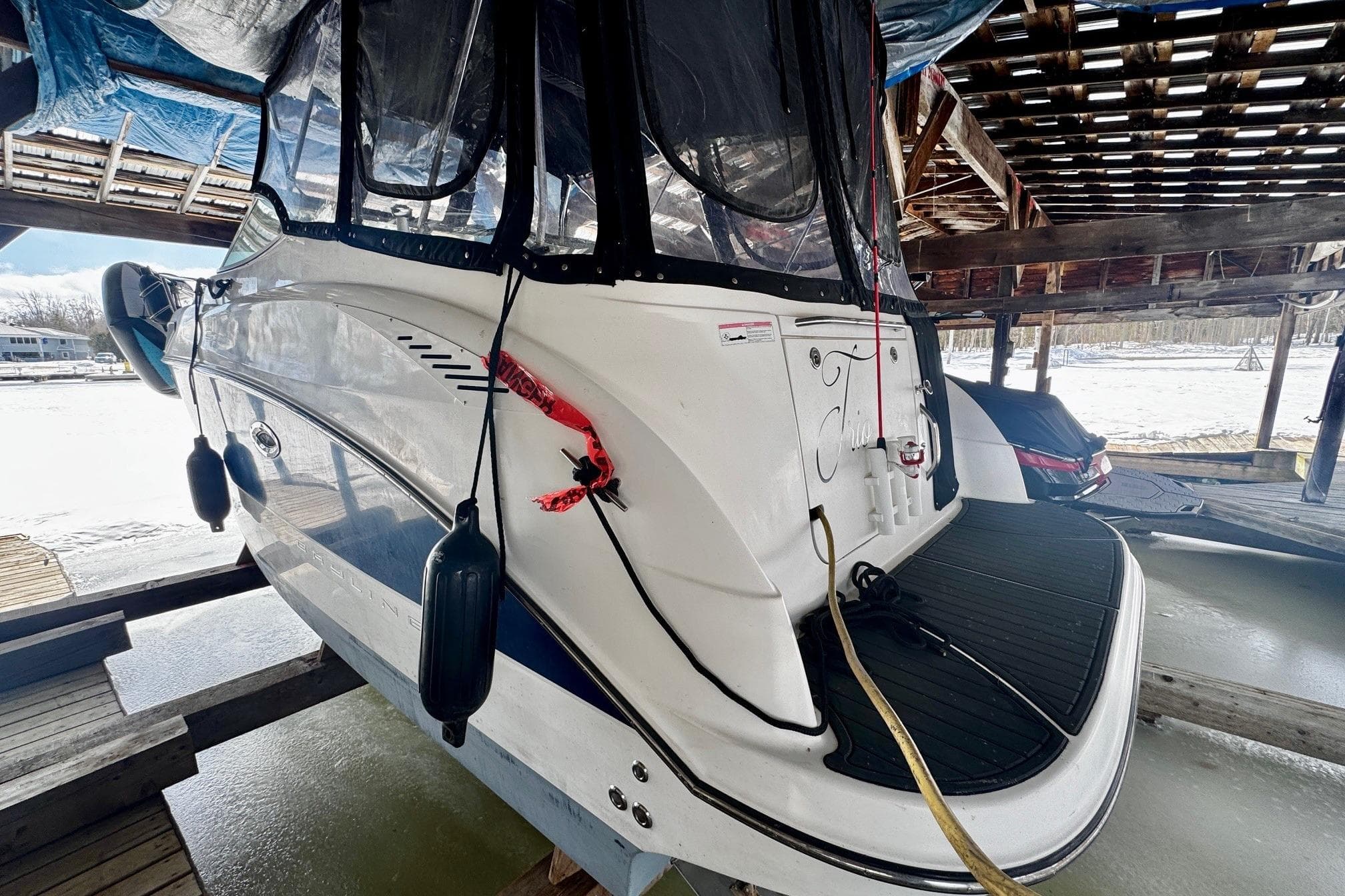 2008 Bayliner 265 boat docked in a covered marina, rear view with protective fenders.