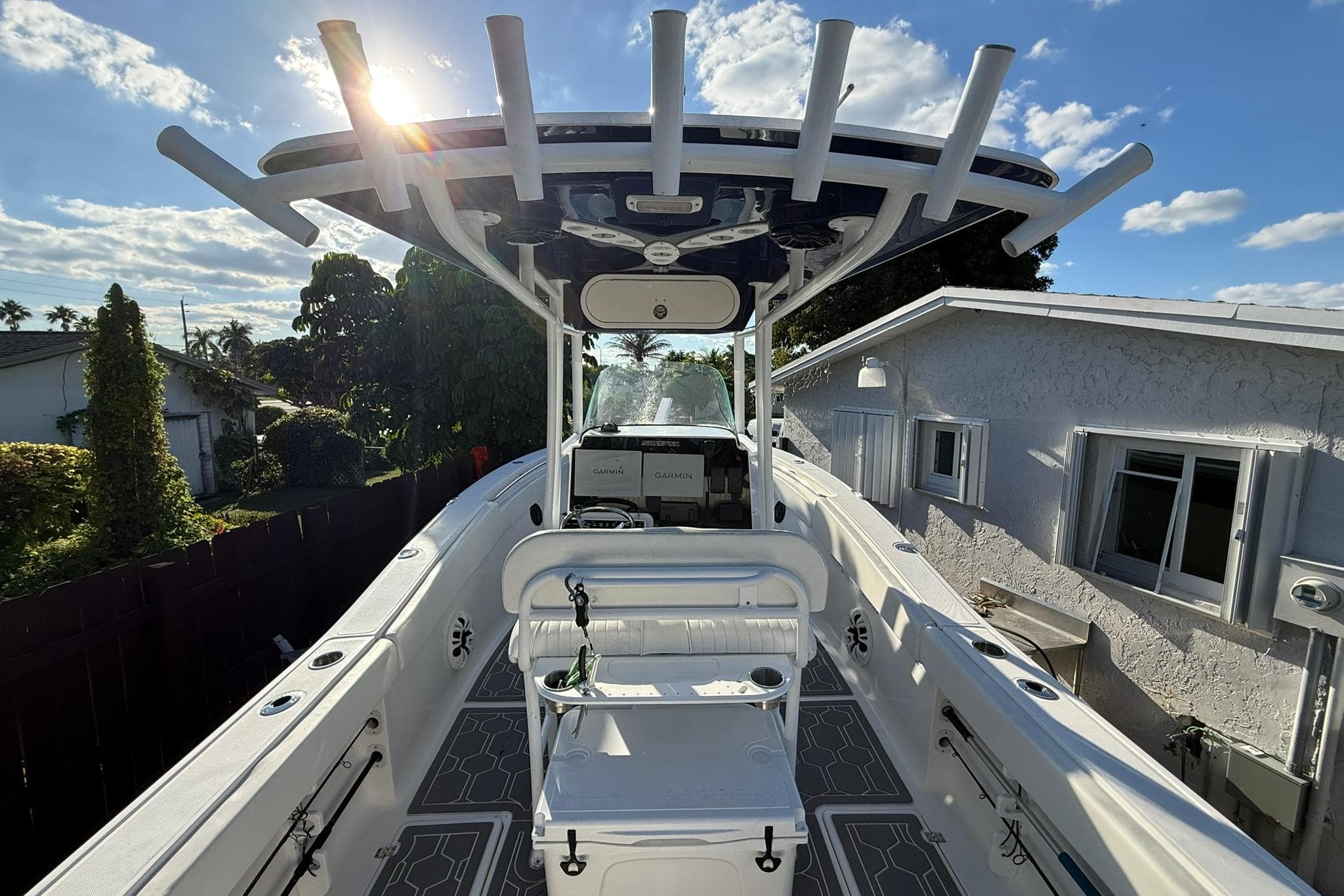 2014 Sea Fox 256 Commander boat with T-top, docked near a house under a sunny sky.