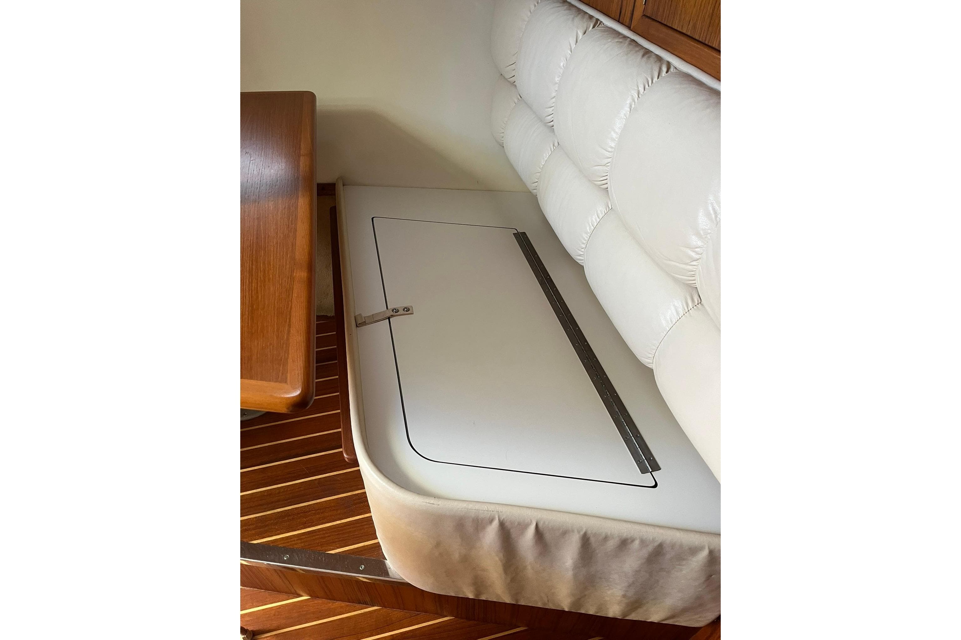 1996 Tiara Yachts 3500 Express interior seating with storage compartment and wooden flooring.