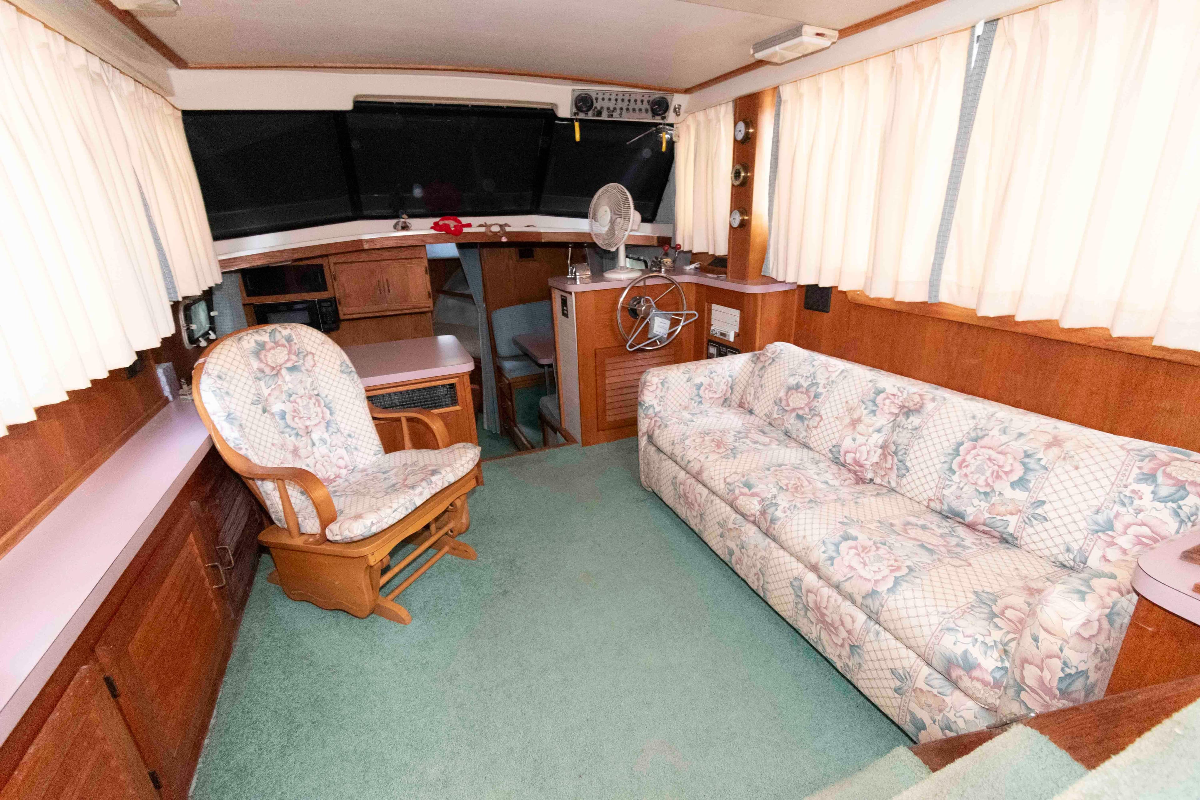 1988 Mainship 36 Double Cabin interior with floral sofa, wooden chair, and helm station.