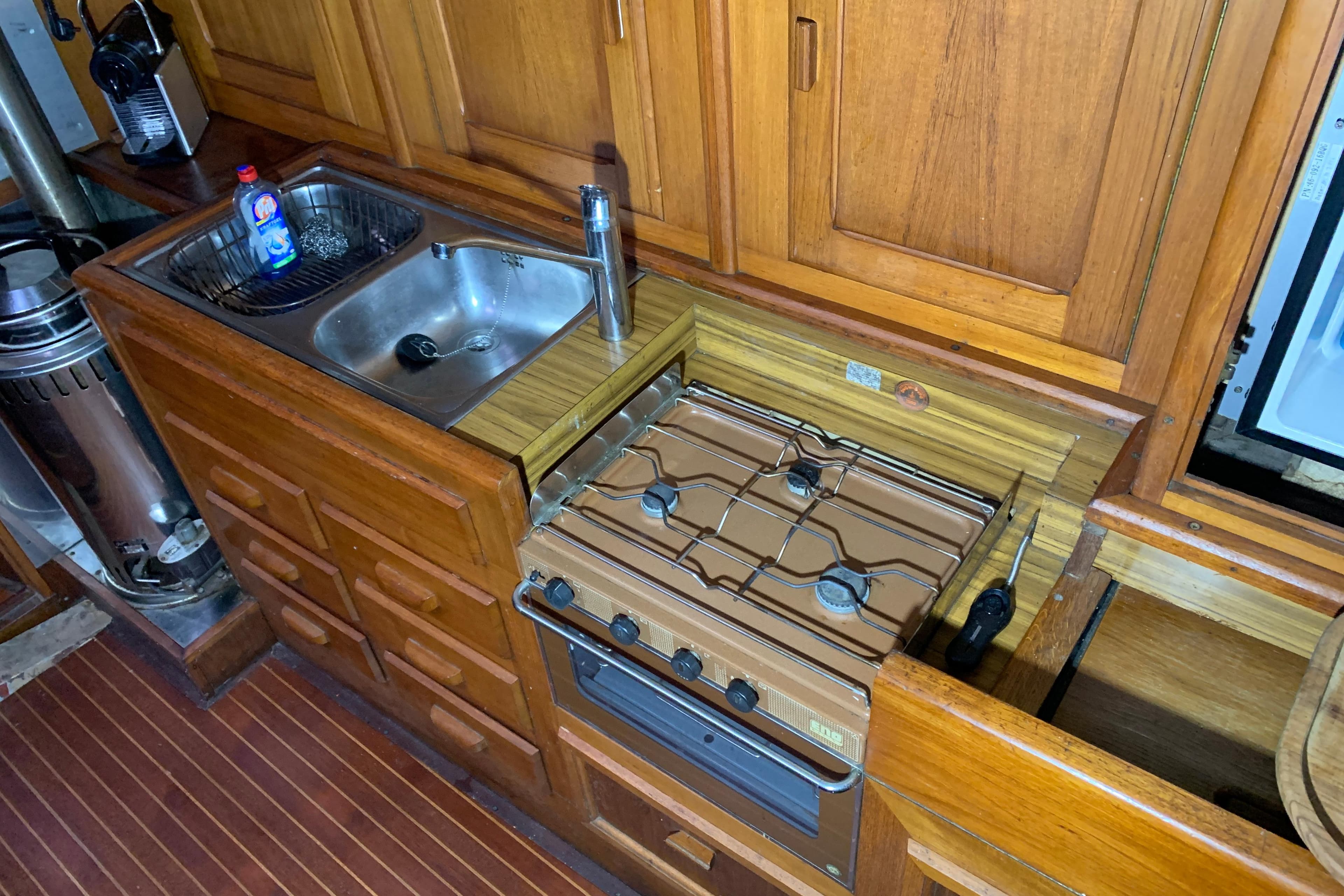 1979 Bueltjer Motorsailer kitchen with wooden cabinetry, sink, and stove.