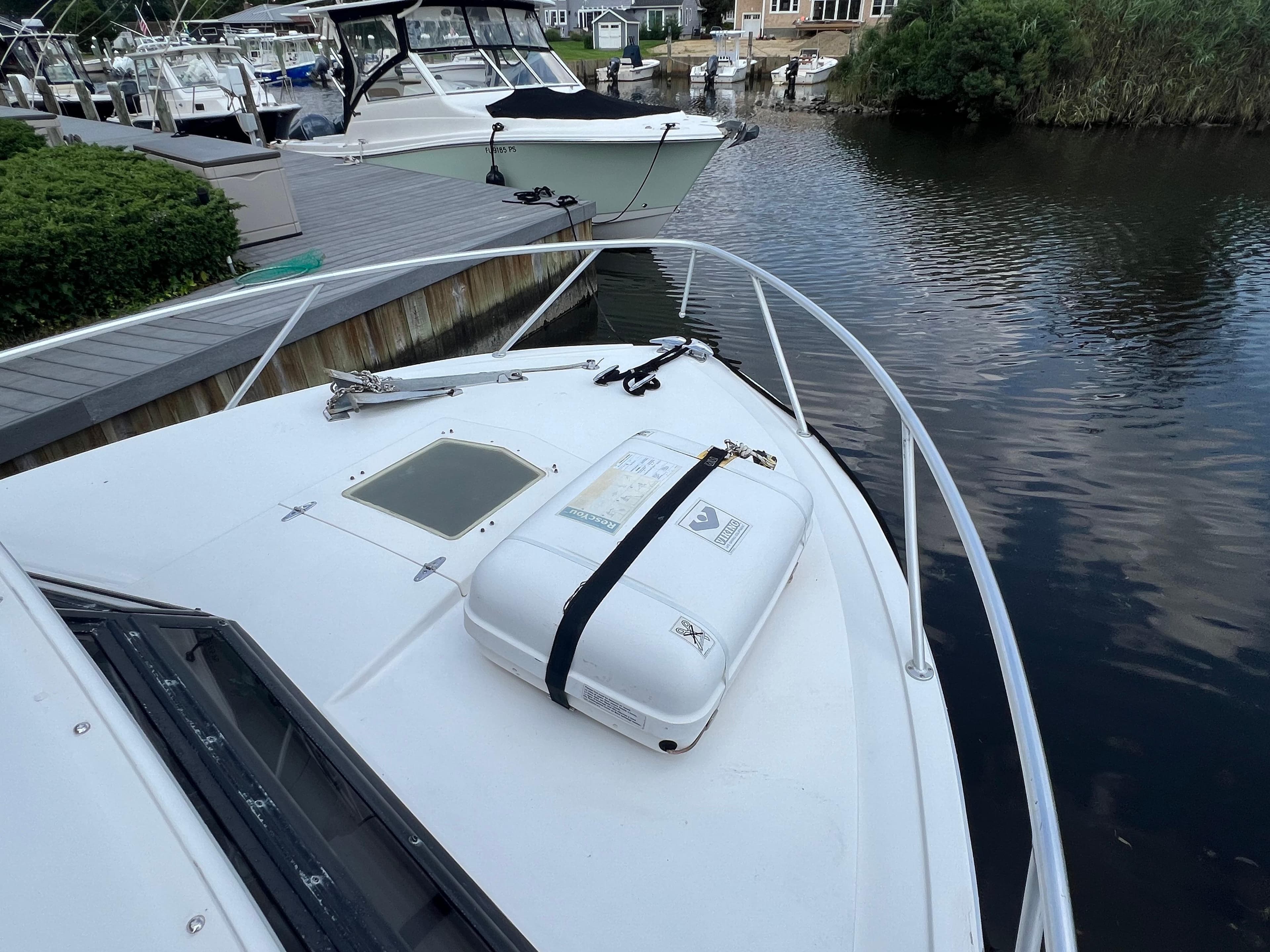 1990 Bertram 28 Flybridge boat docked by a calm waterfront.