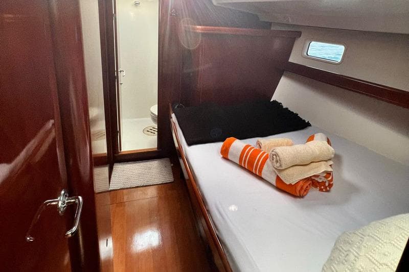 Cozy cabin interior of 2006 Beneteau Oceanis Clipper 523 with bed and ensuite bathroom.