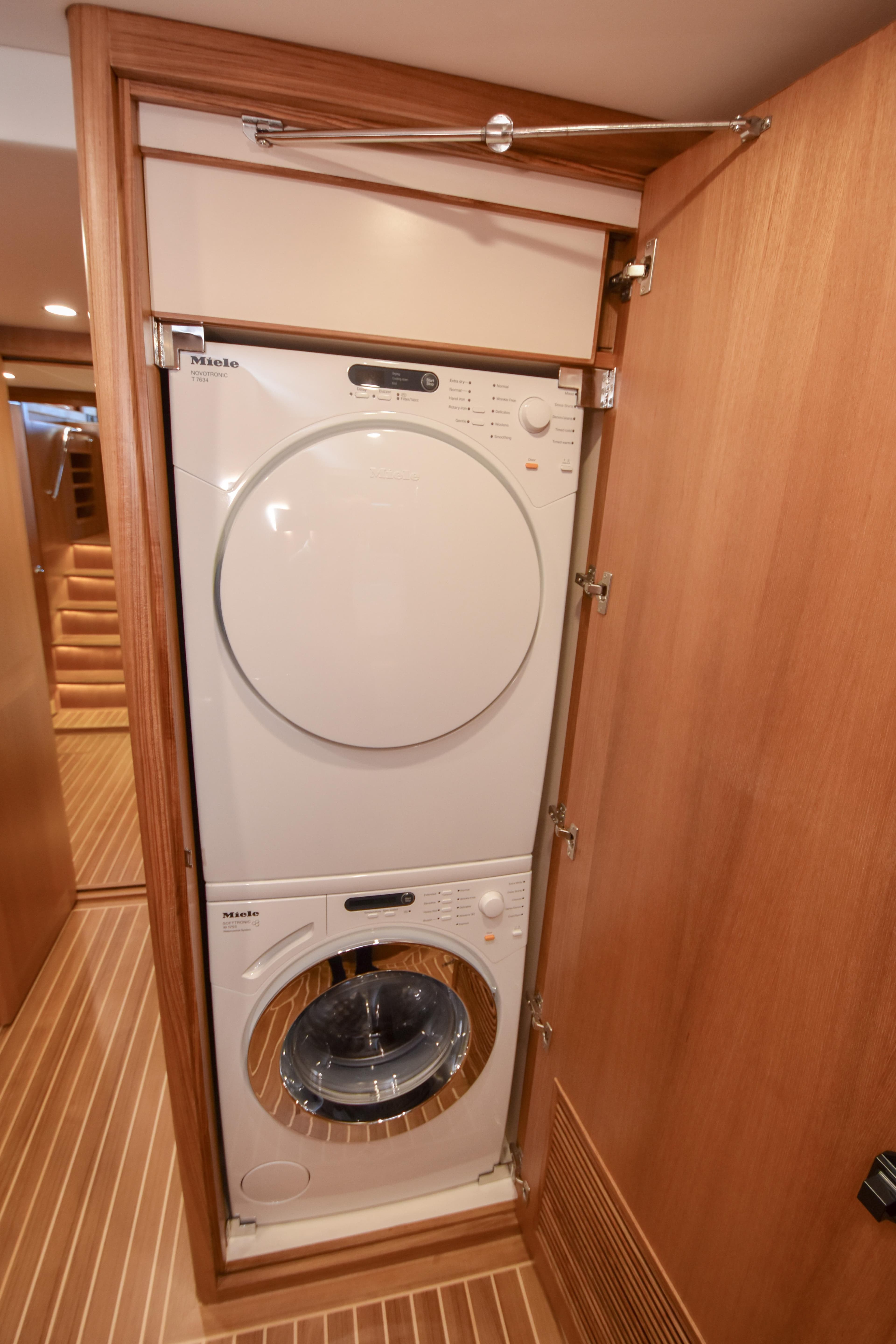 Stacked washer and dryer in a Fleming 78 yacht, 2020 model, with wooden cabinetry.