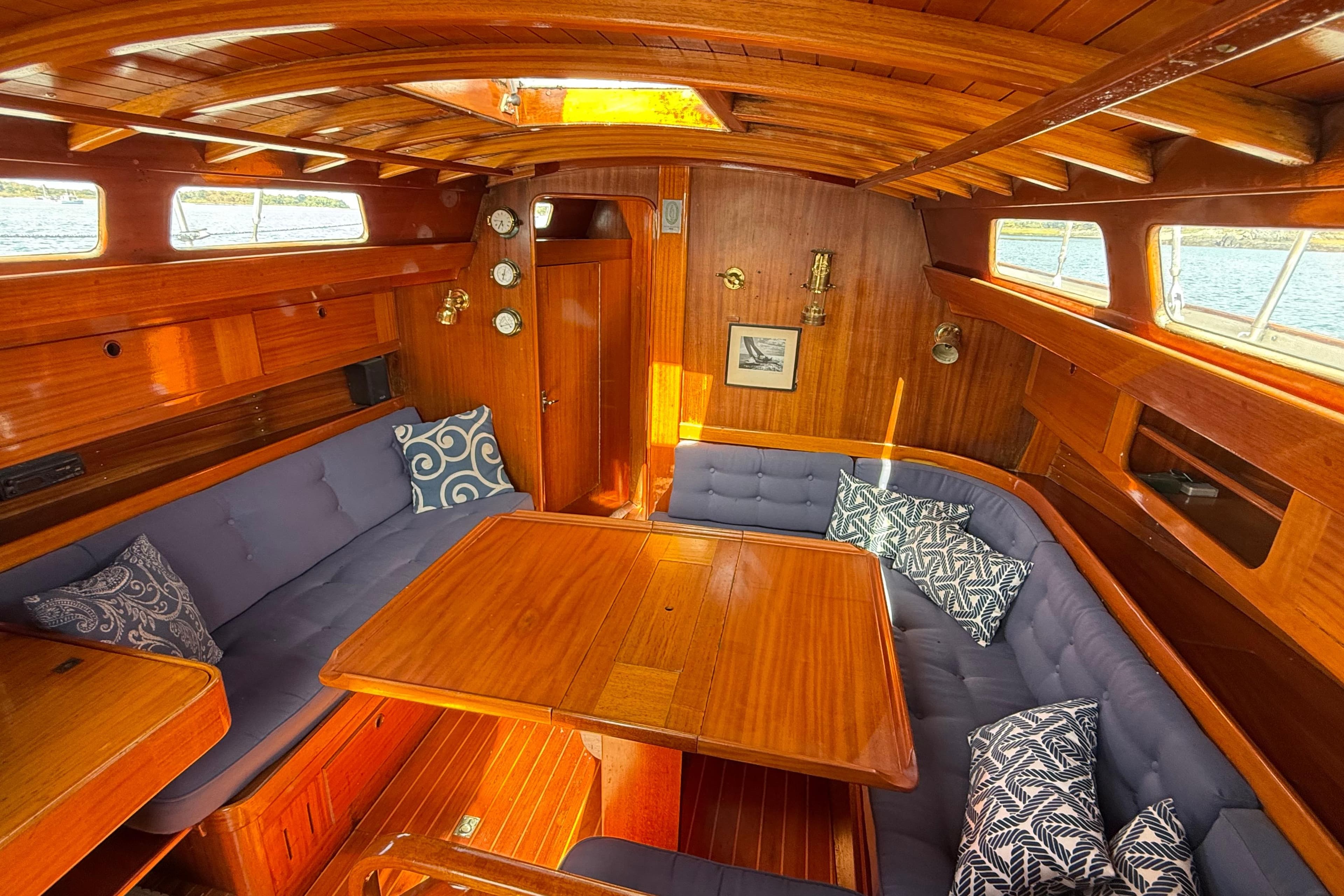 Cozy interior of a 1986 Vindo 45 sailboat with wooden finish and cushioned seating.