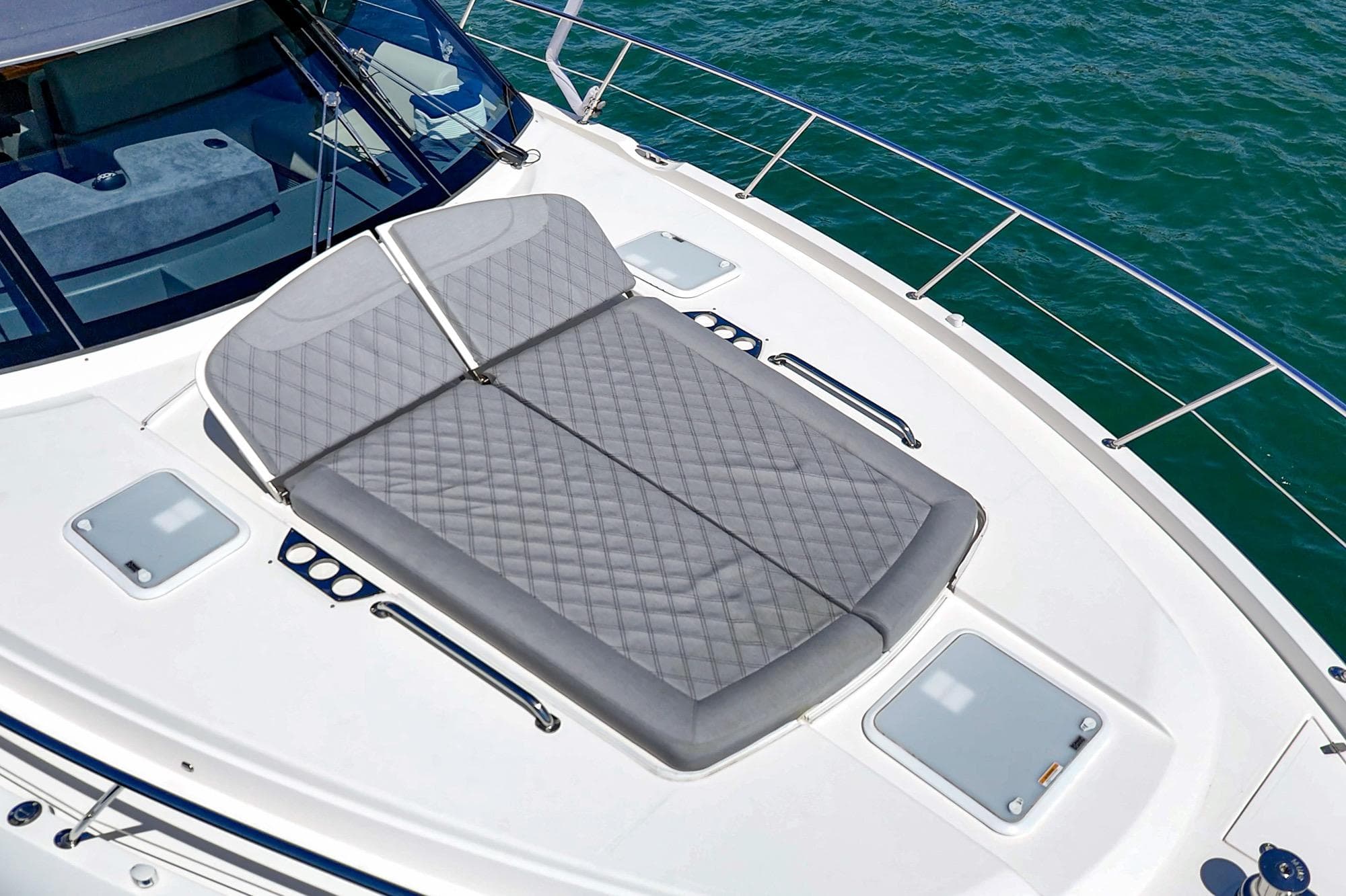 2024 Riviera 5400 Sport Yacht sunpad on deck, overlooking ocean waters.